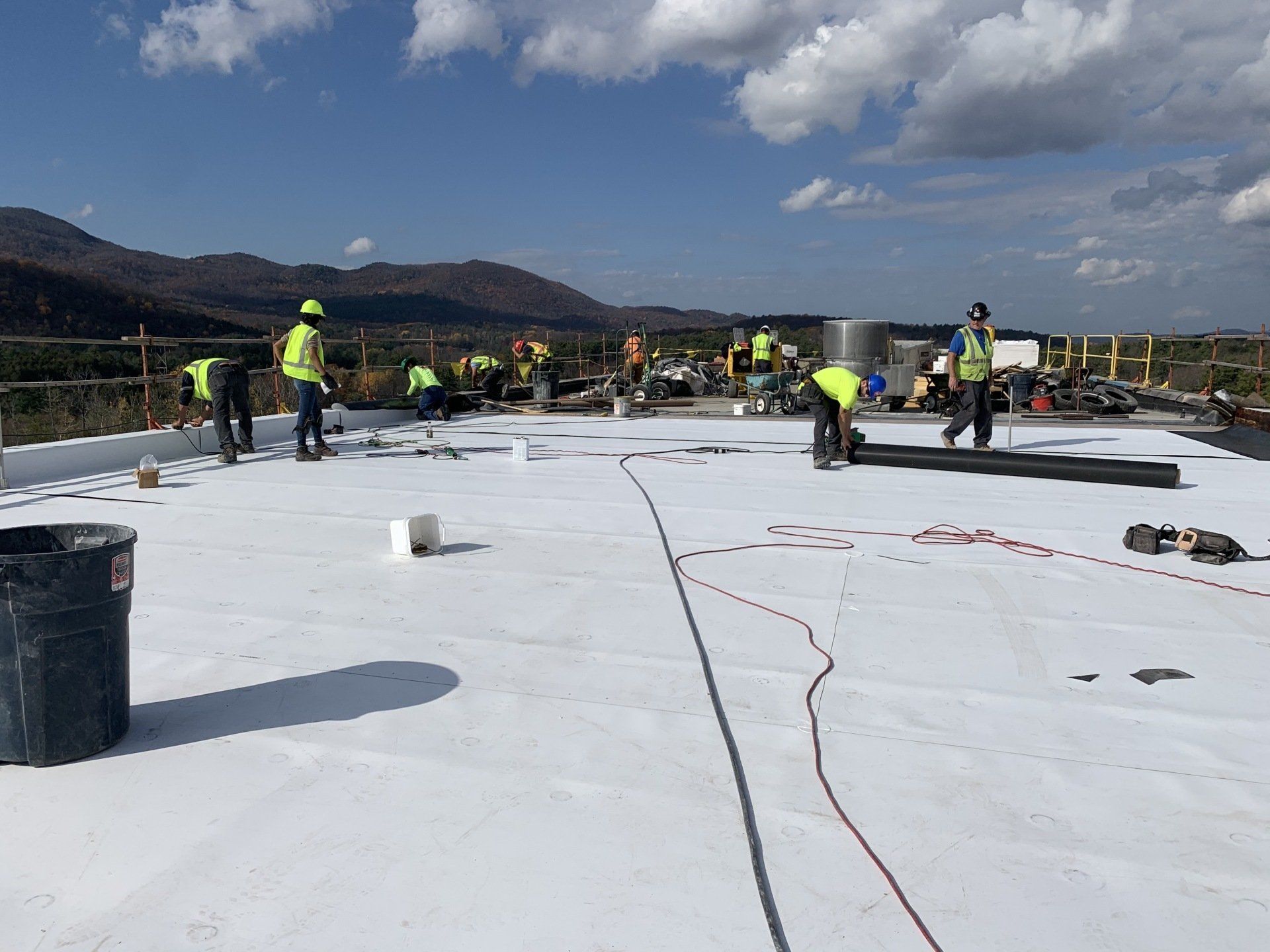 A group of construction workers are working on a white roof.