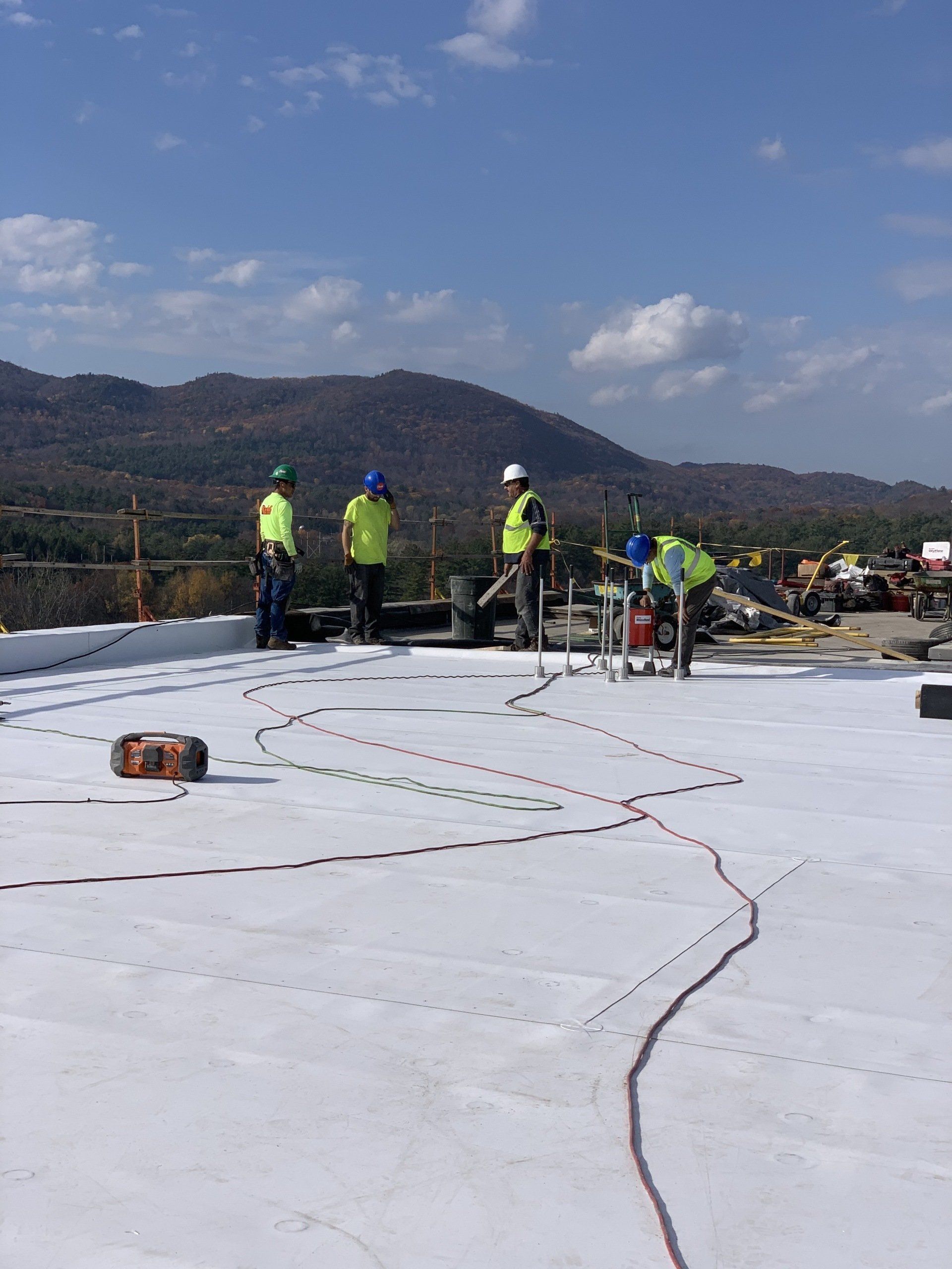 A group of construction workers are working on a white roof.