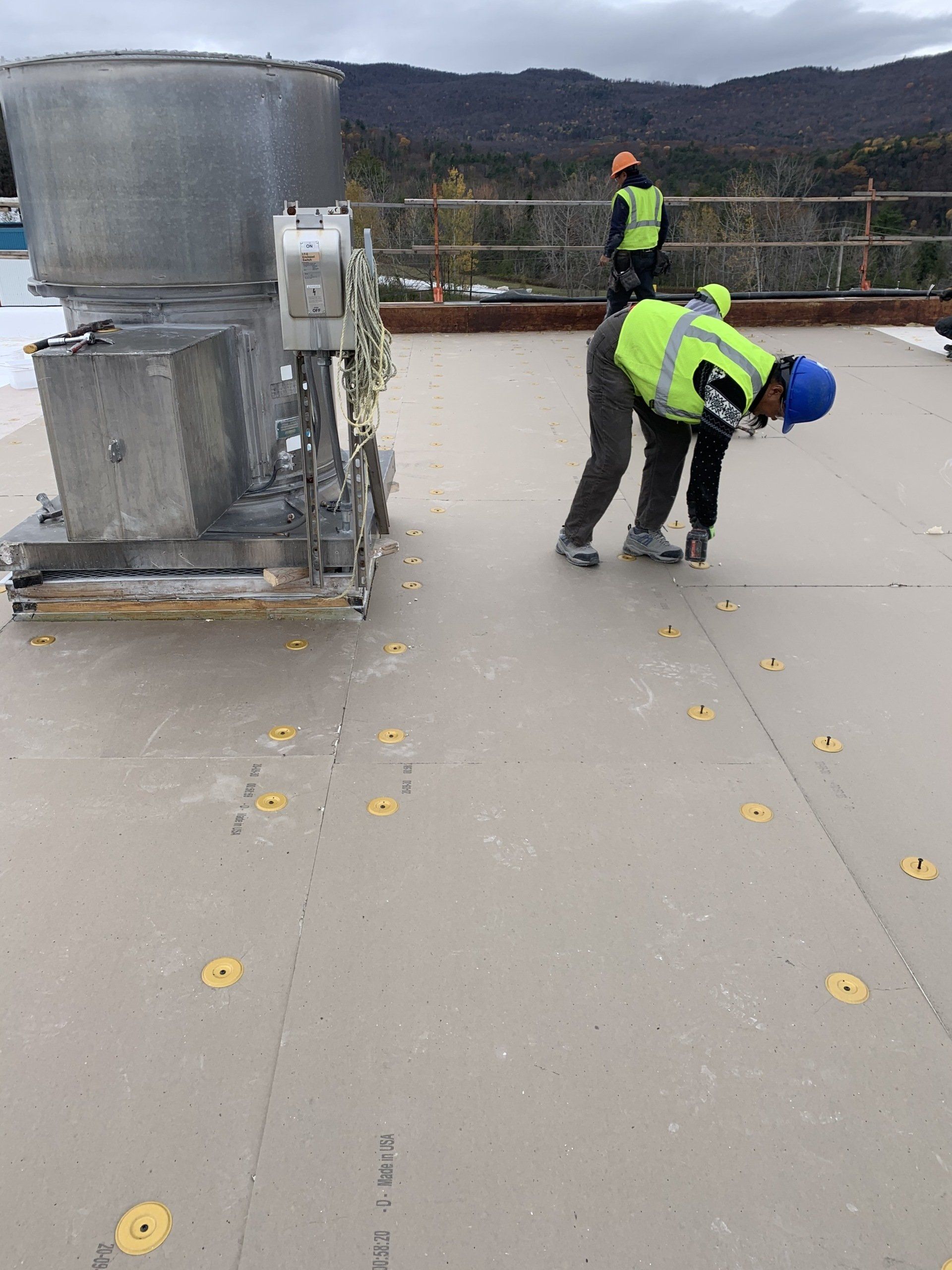 Two construction workers are working on a roof.