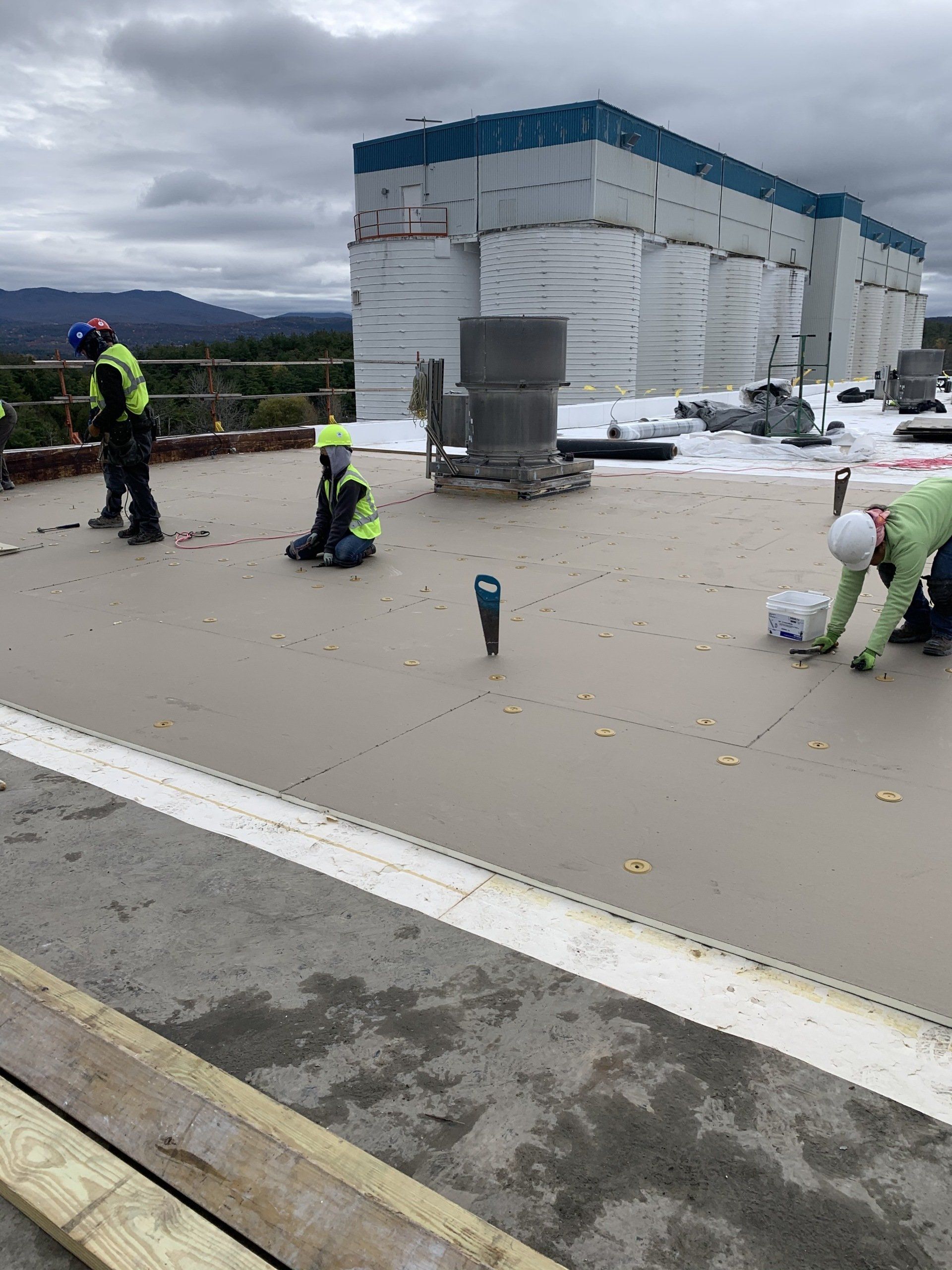 A group of construction workers are working on the roof of a building.