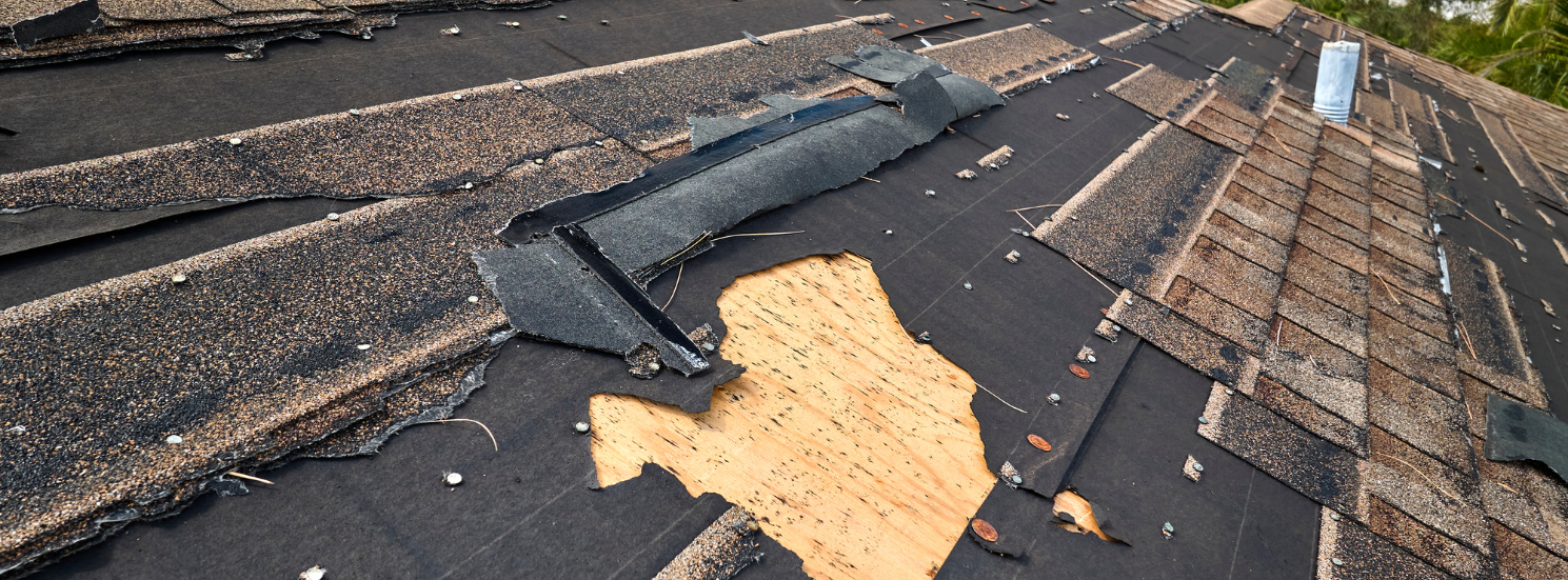 A severely damaged roof in Vermont with many shingles missing.