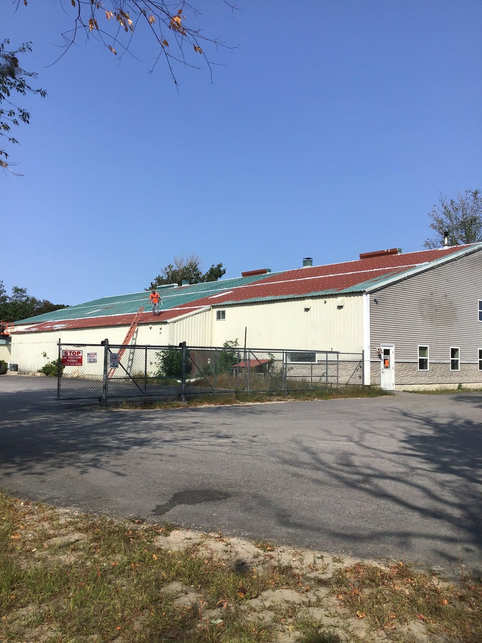 A large white building with a red roof is sitting in a parking lot.
