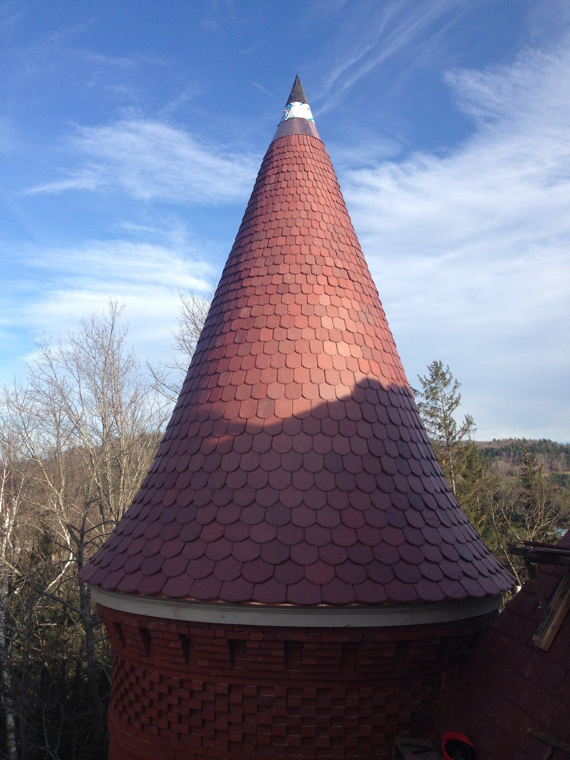 A brick tower with a red cone shaped roof