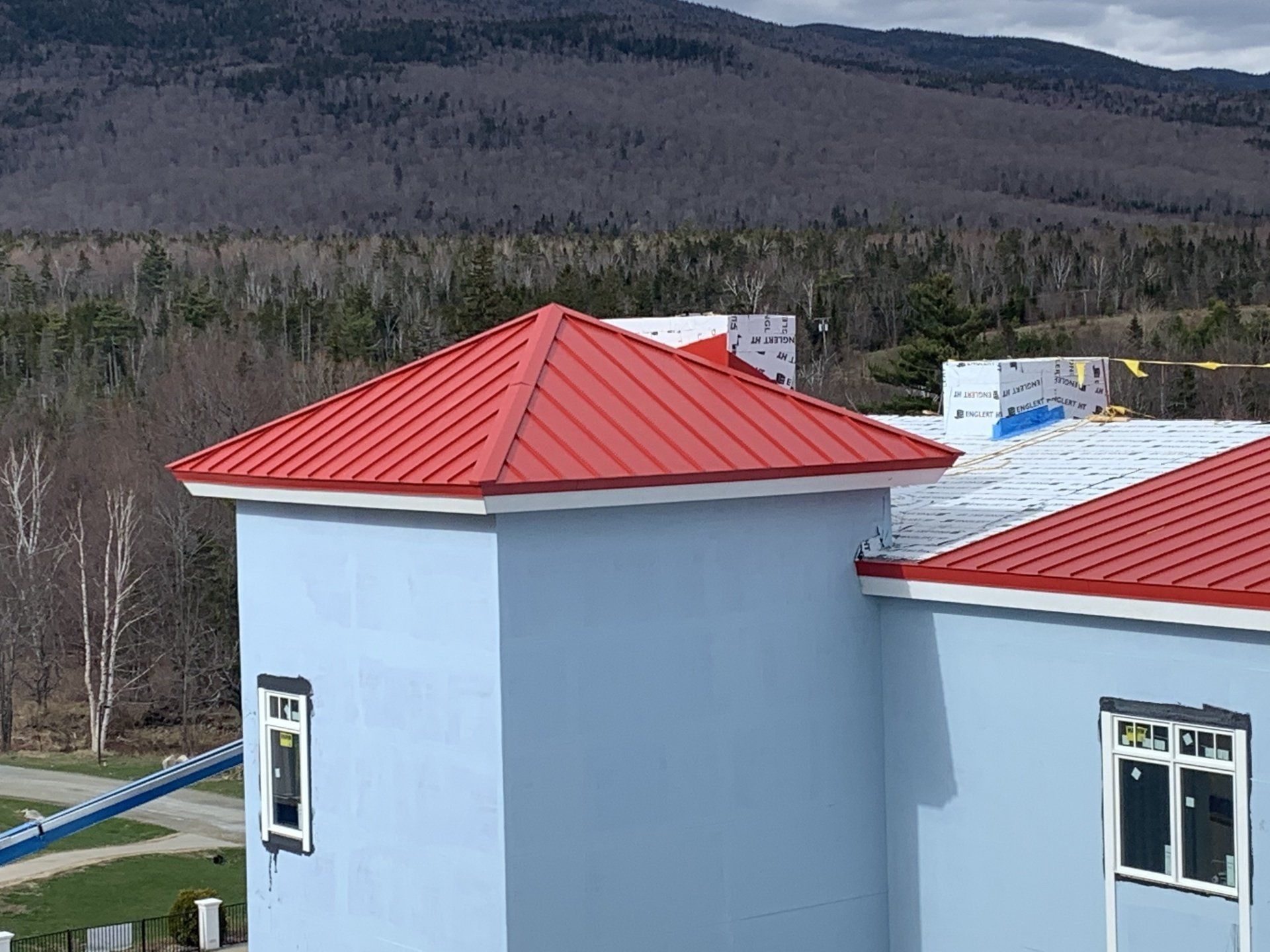 A blue building with a red roof and mountains in the background