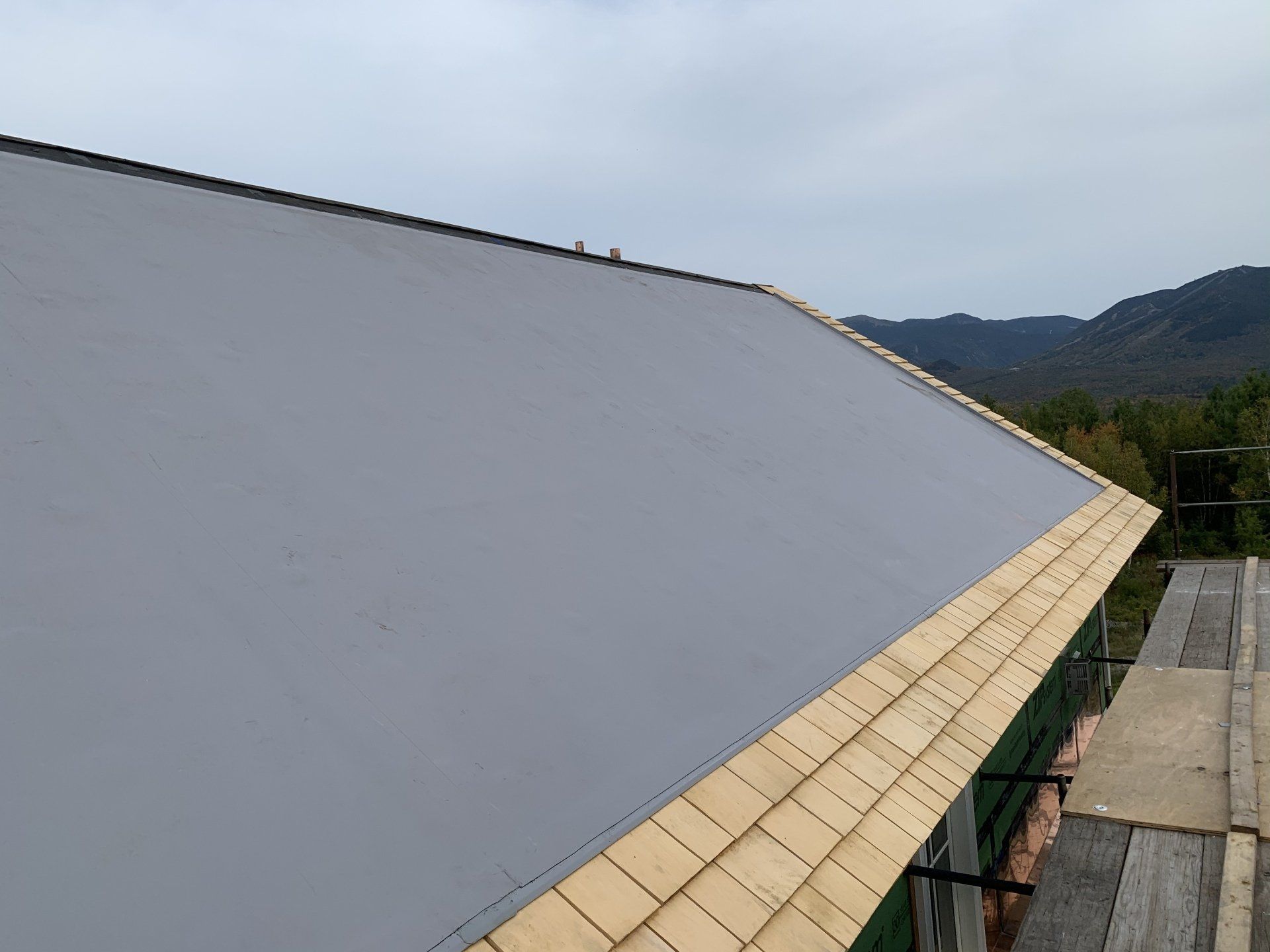 The roof of a building is being built with wooden shingles.