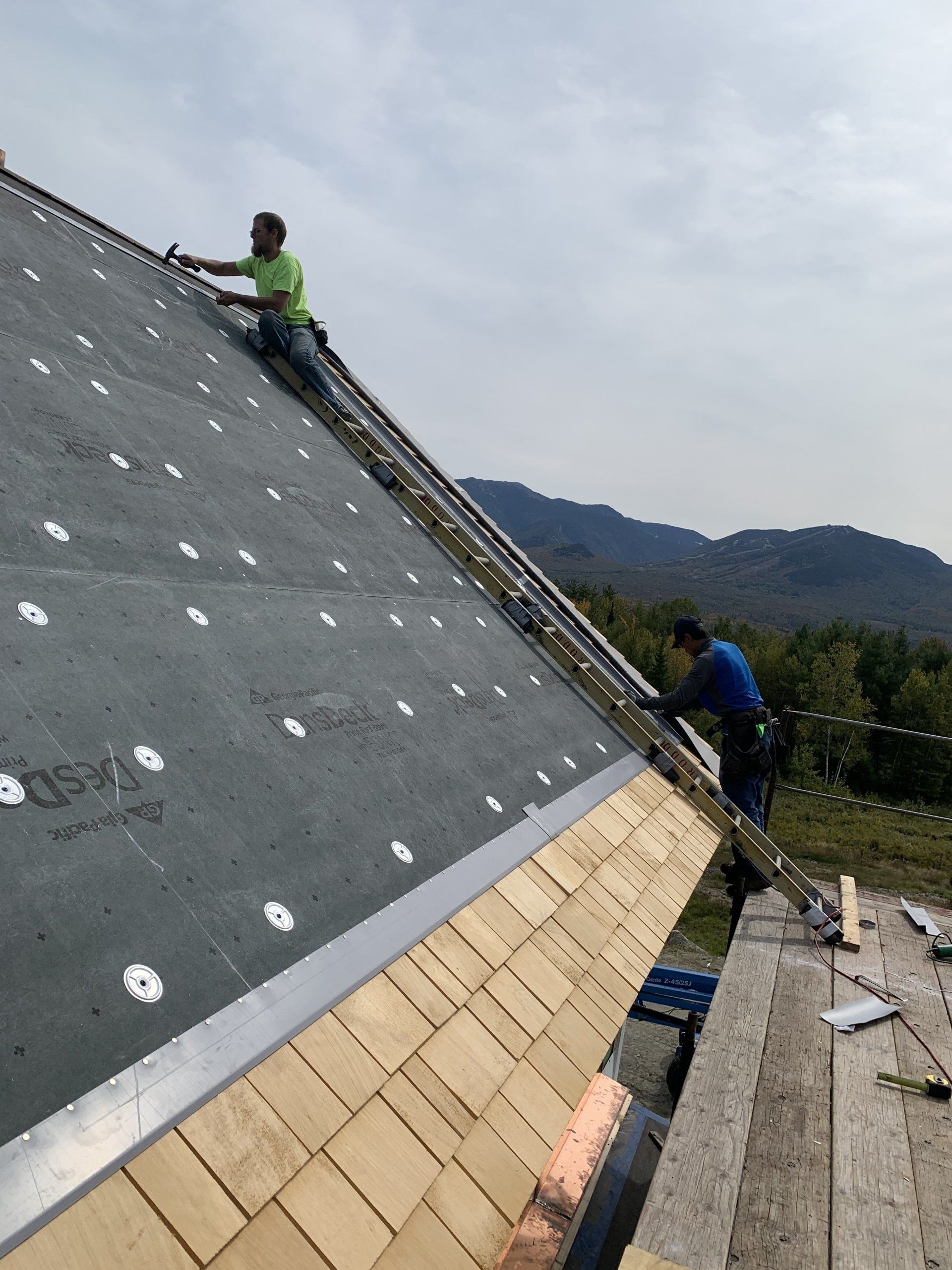 Two men are working on the roof of a building.