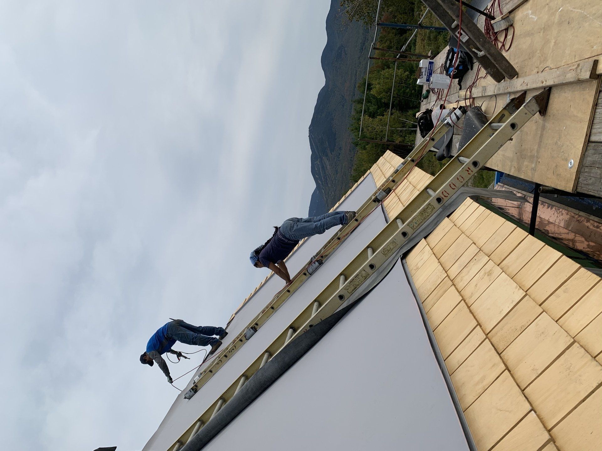Two men are working on the roof of a building.