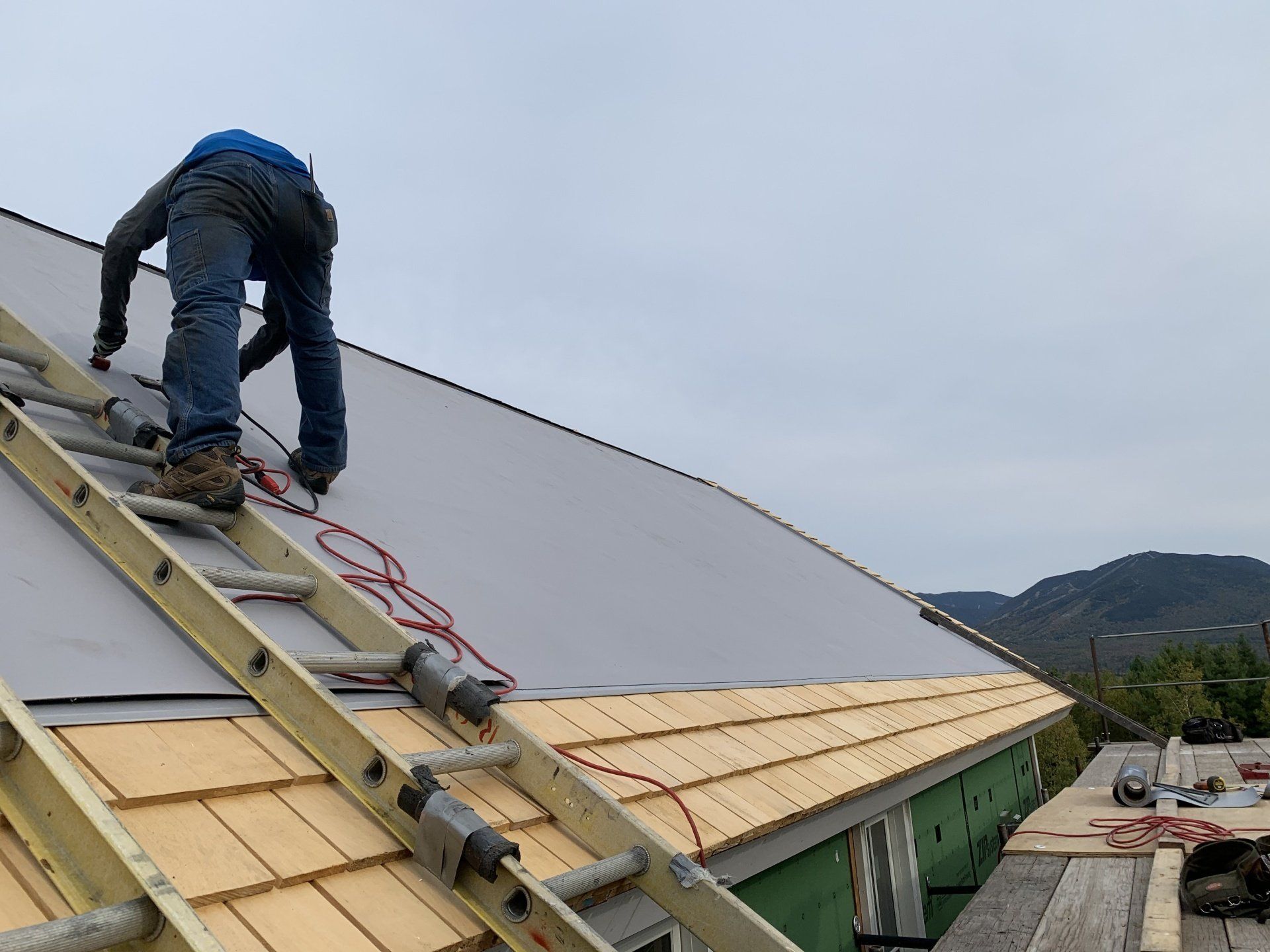 A man is working on the roof of a building with a ladder.
