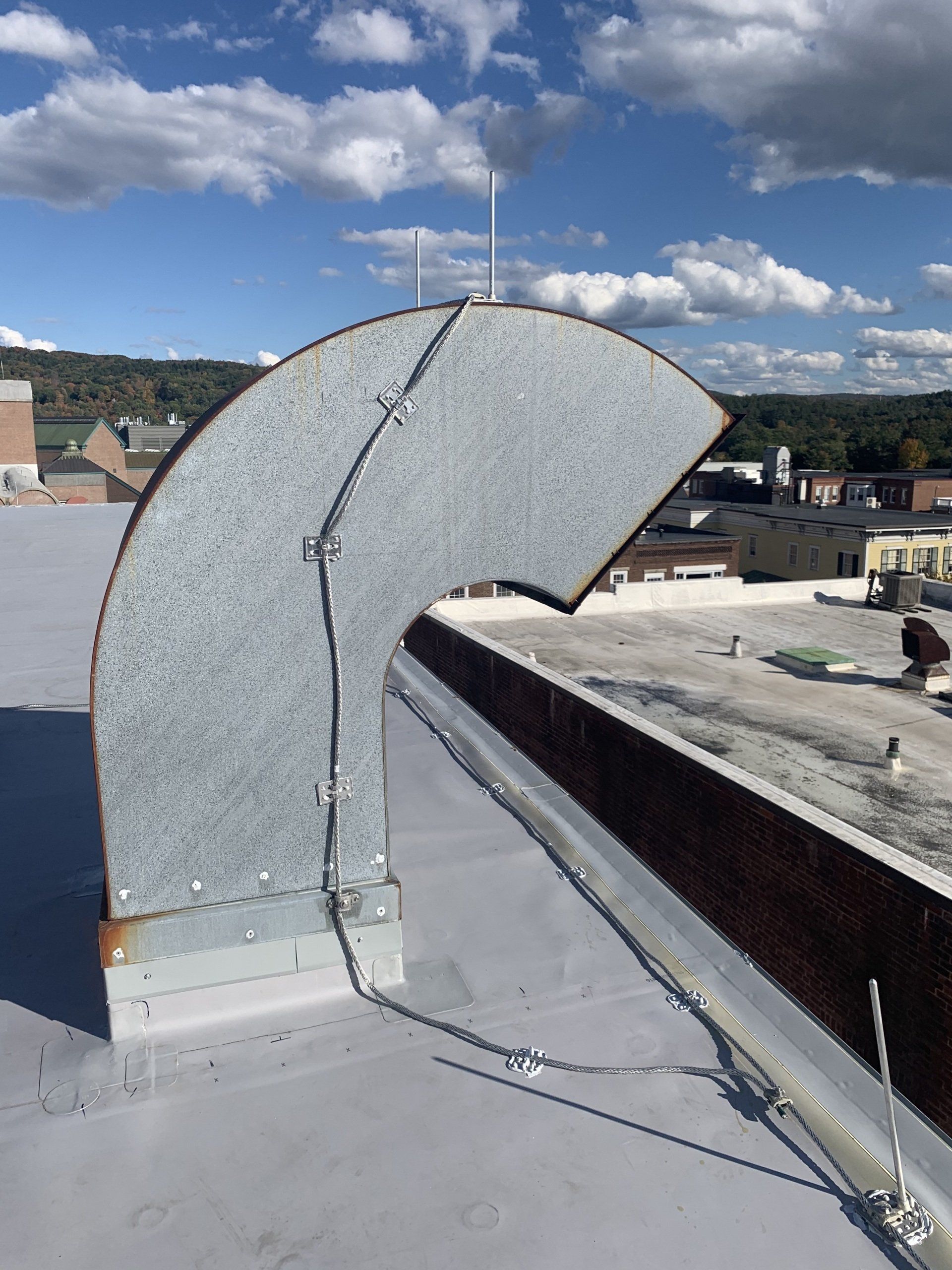 A metal pipe is sitting on top of a roof.