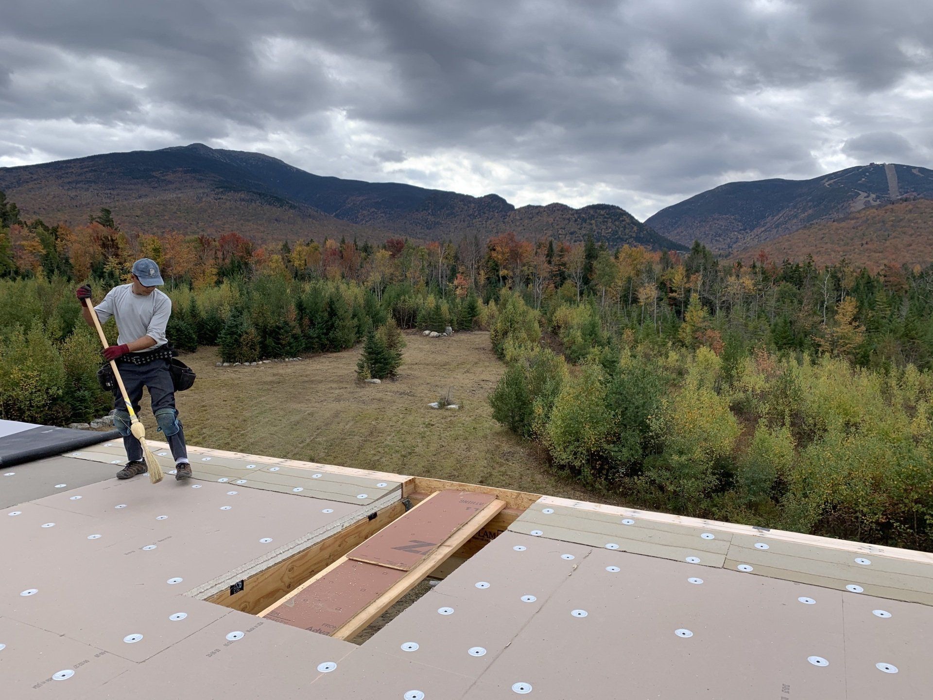 A man is standing on a roof with a broom.