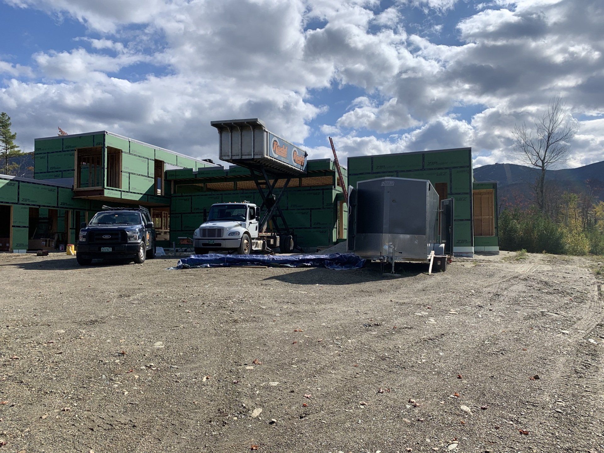 A truck and trailer are parked in front of a building under construction.