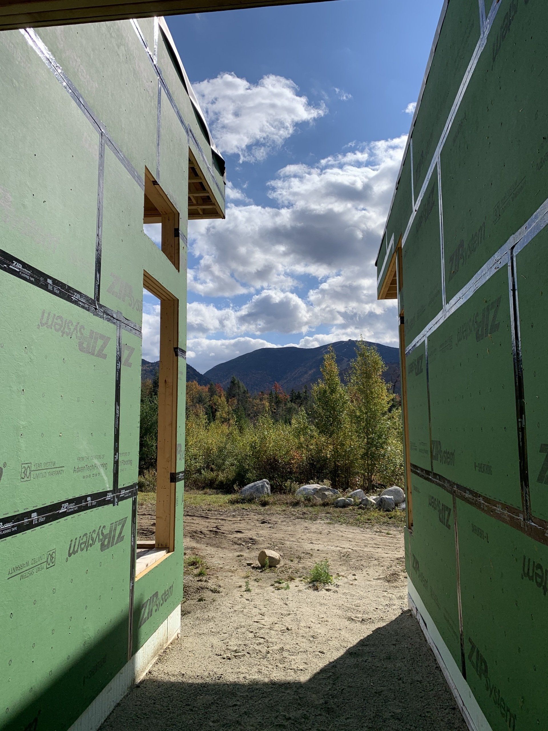A building under construction with green walls and mountains in the background