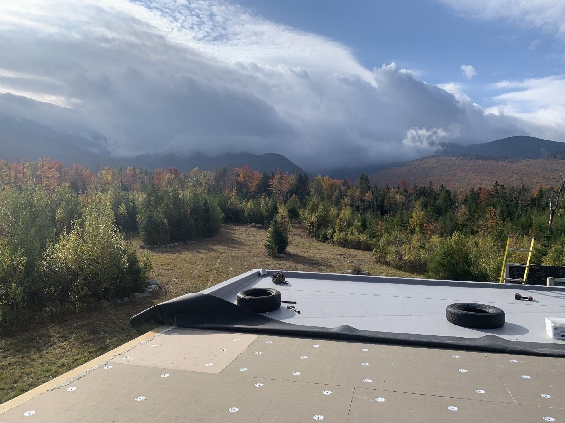 A roof with a view of a forest and mountains in the background.