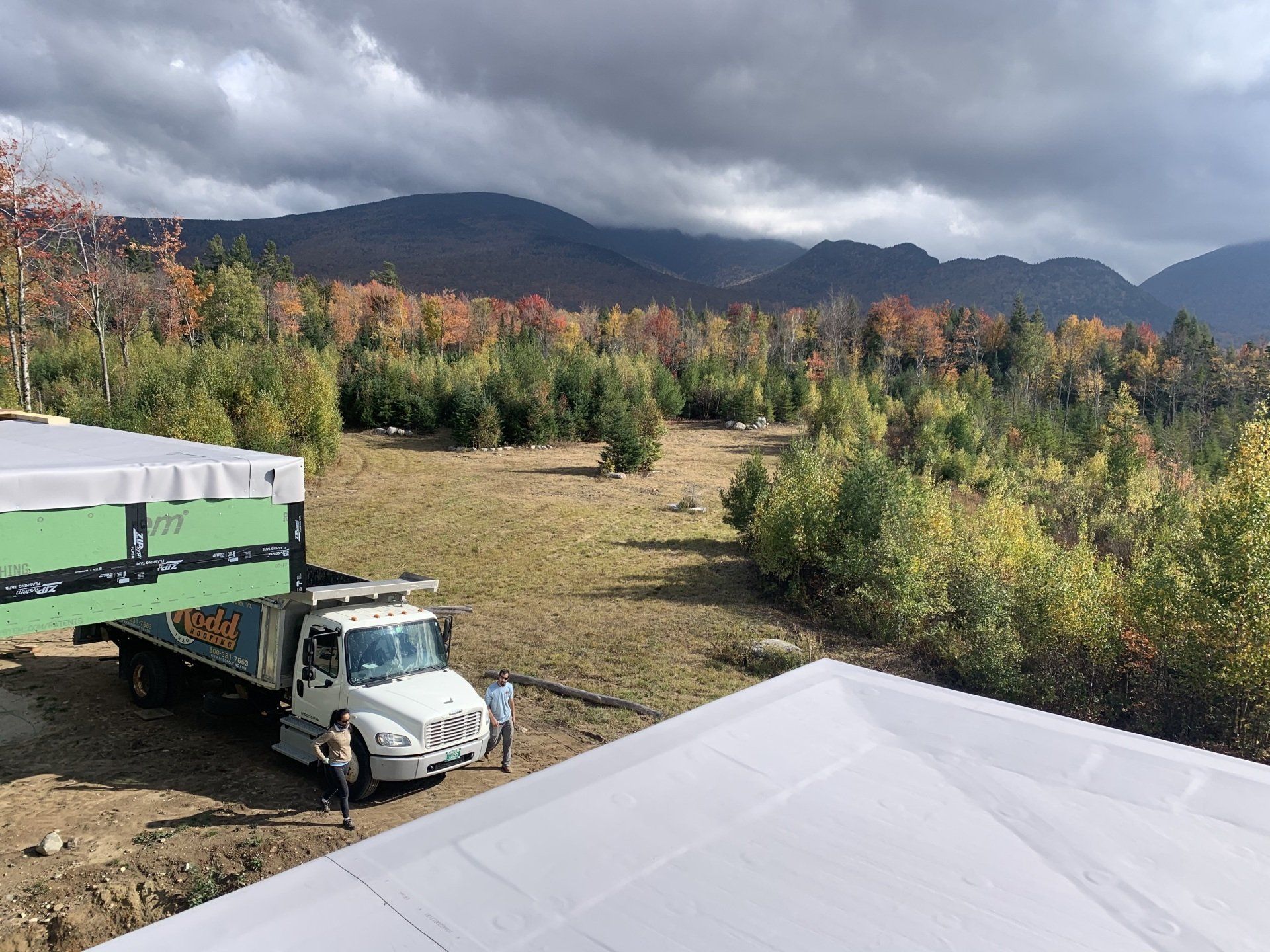 A TPO/PVC roof with a view of the mountains and a Rood Roofing truck