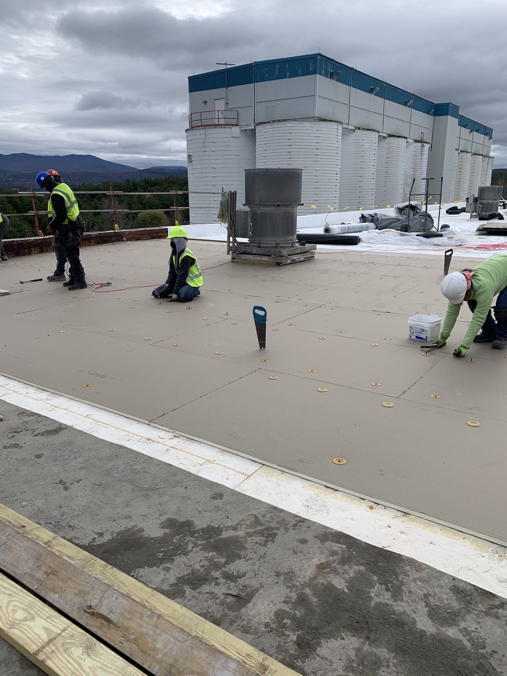 A group of construction workers are working on the roof of a building.