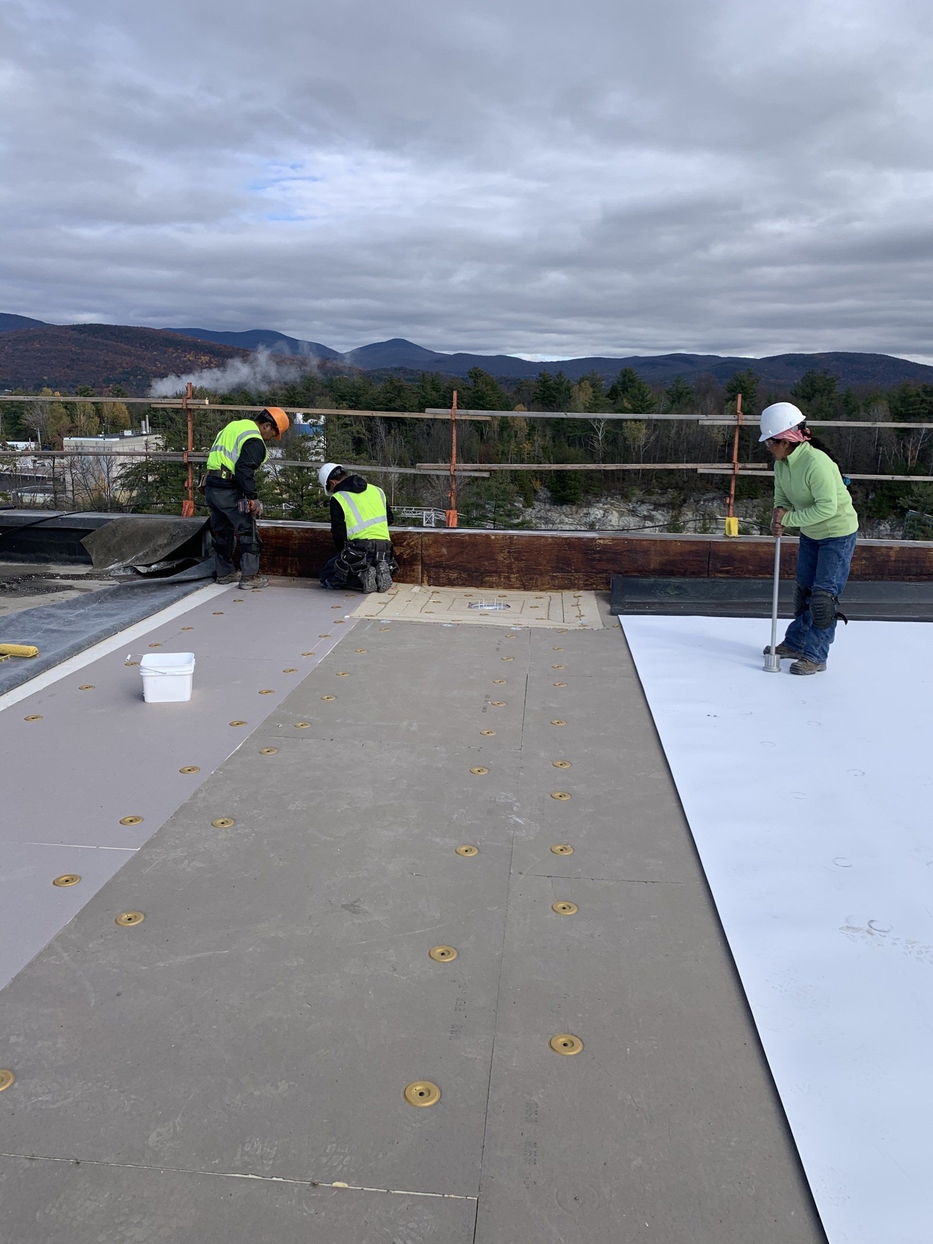 A group of construction workers are working on a roof.