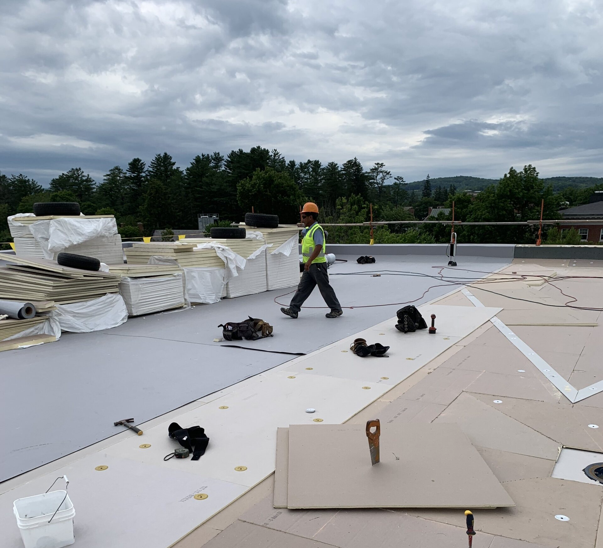 A Rodd Roofing expert on a commercial roof surrounded by roofing supplies in northern Vermont. 