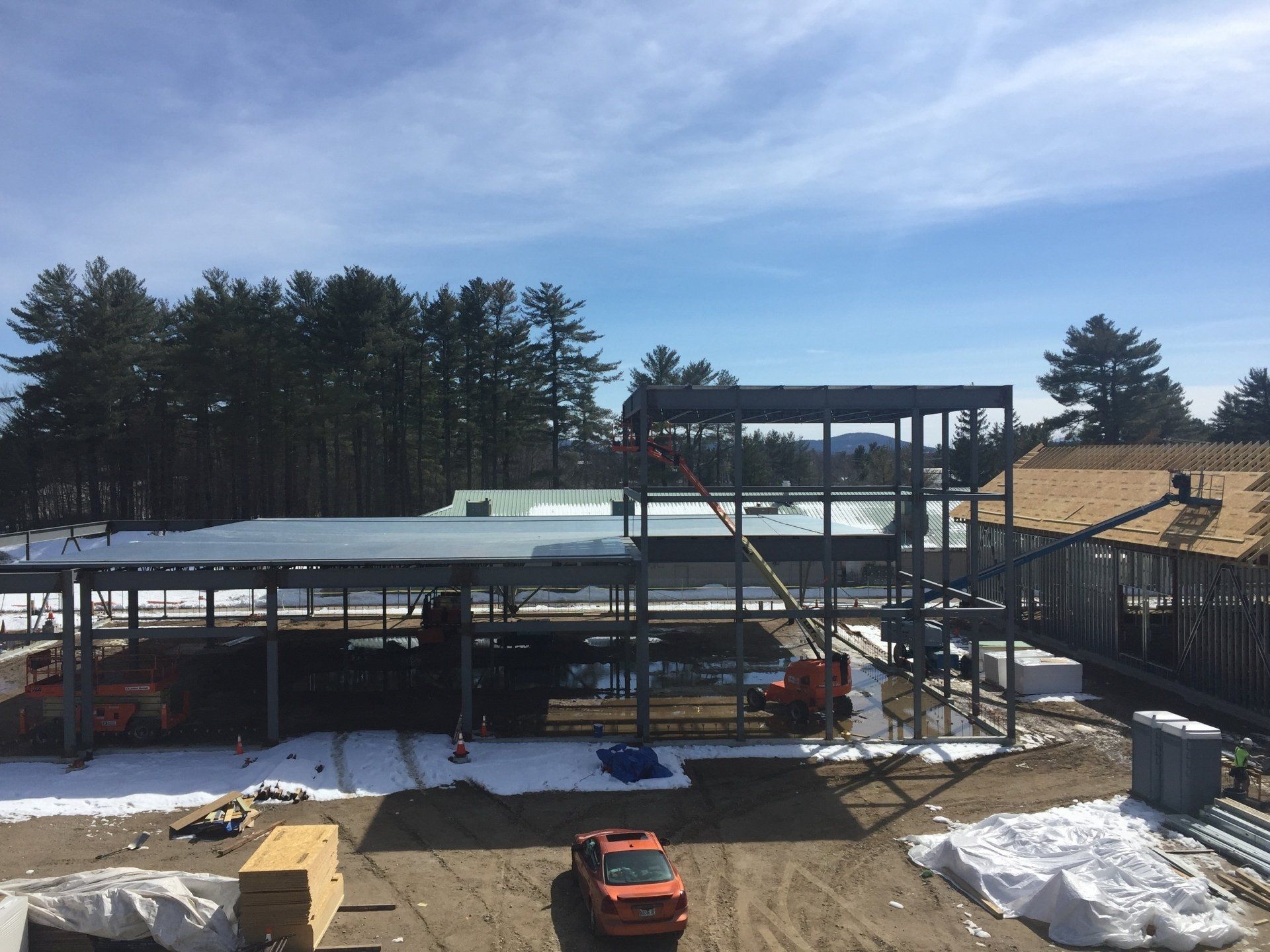 A car is parked in front of a building under construction.