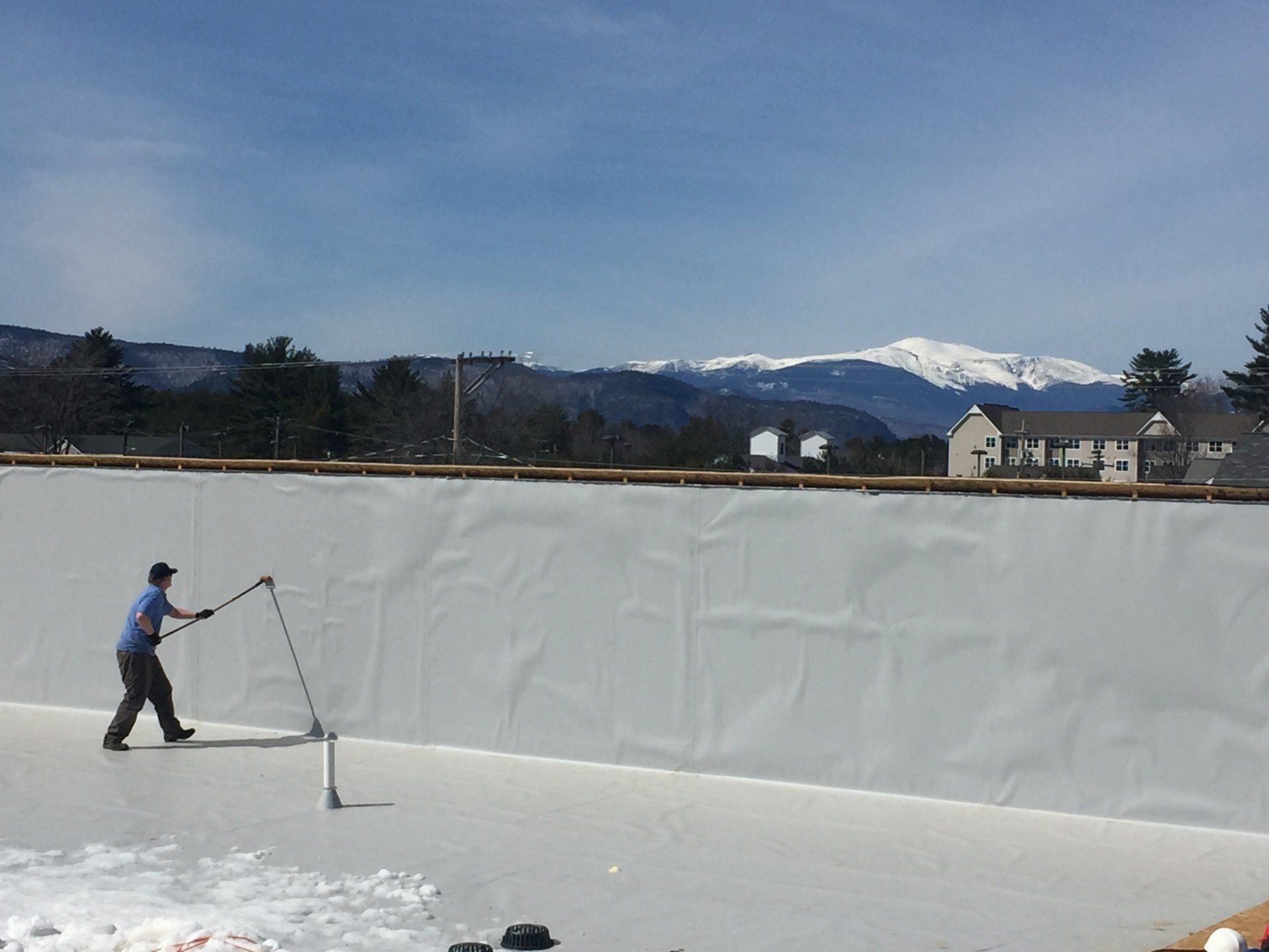 A man is standing on a ice rink with mountains in the background