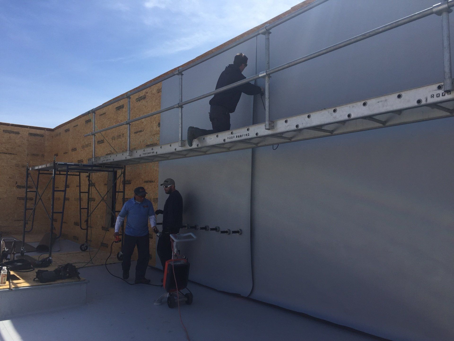 Two men are working on a wall with a ladder.