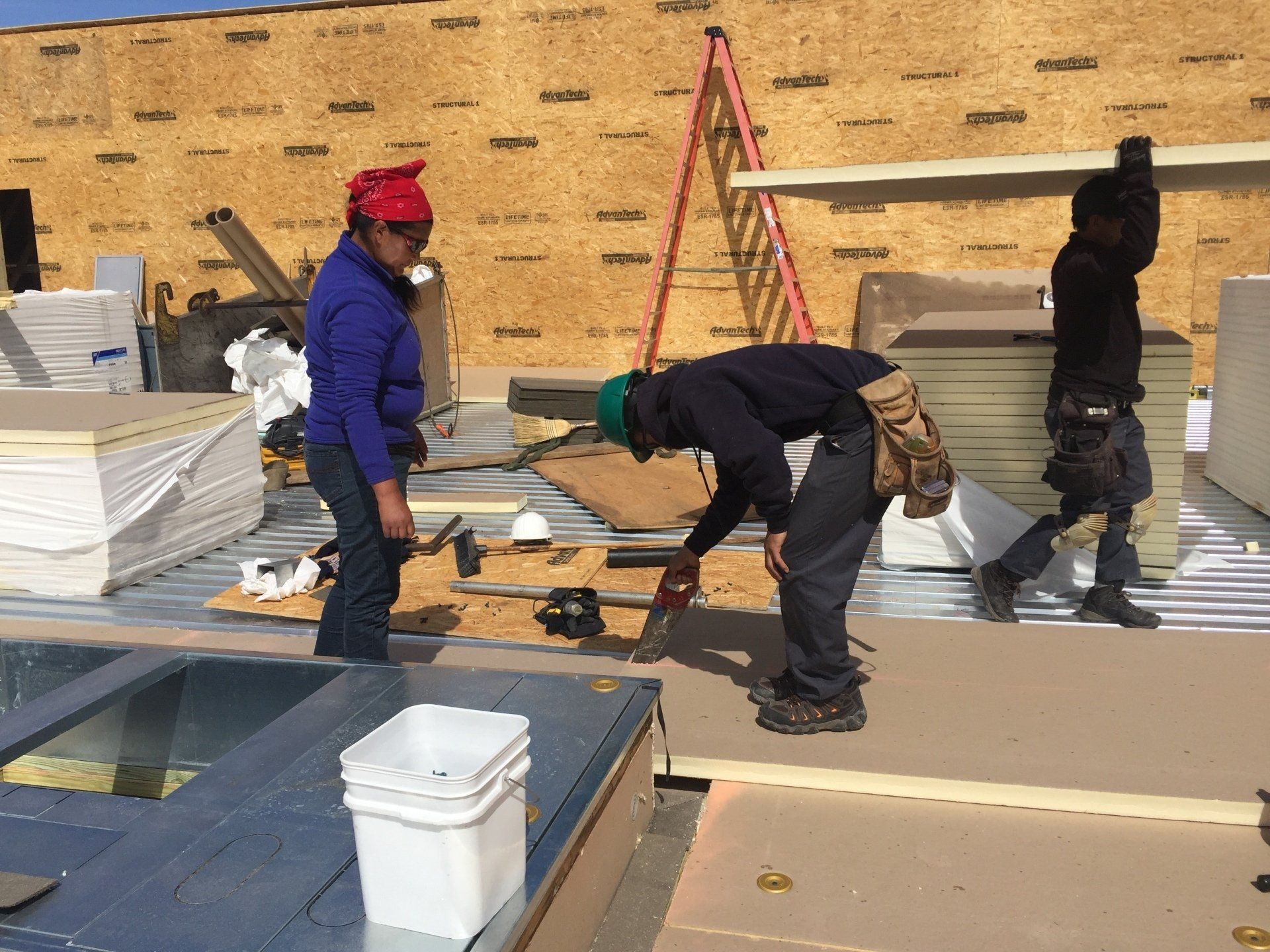 A group of construction workers are working on the roof of a building.