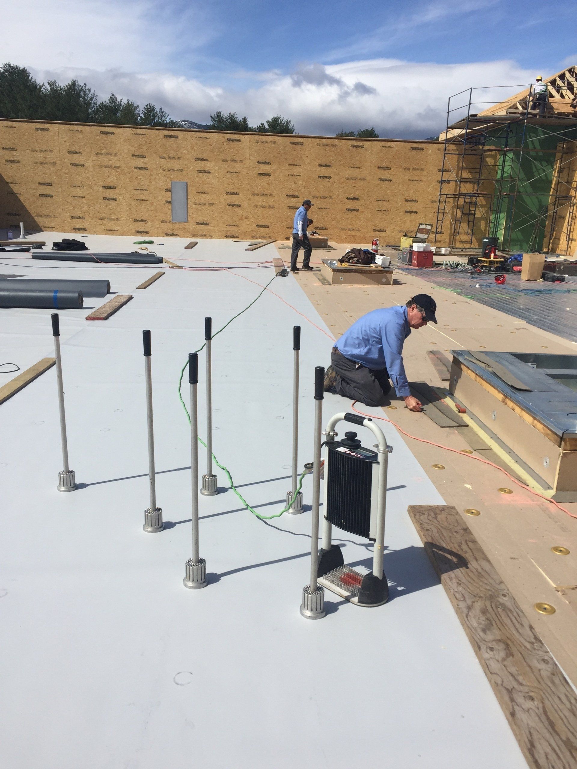 A roofer from Rodd Roofing is kneeling down on a commercial flat roof