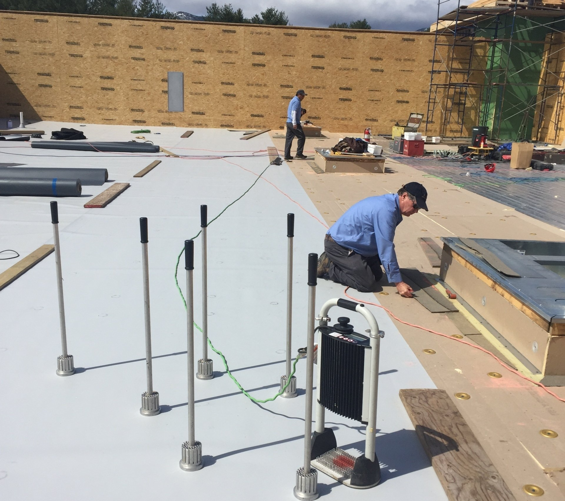 Two Rodd Roofing contractors installing new roofing on a commercial roof in Vermont. 