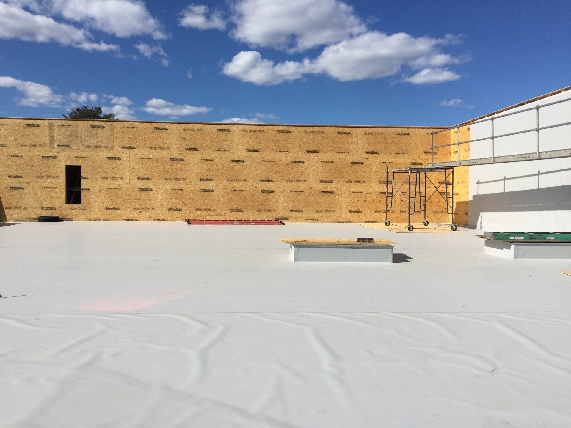 A building under construction with a white roof and a blue sky in the background.