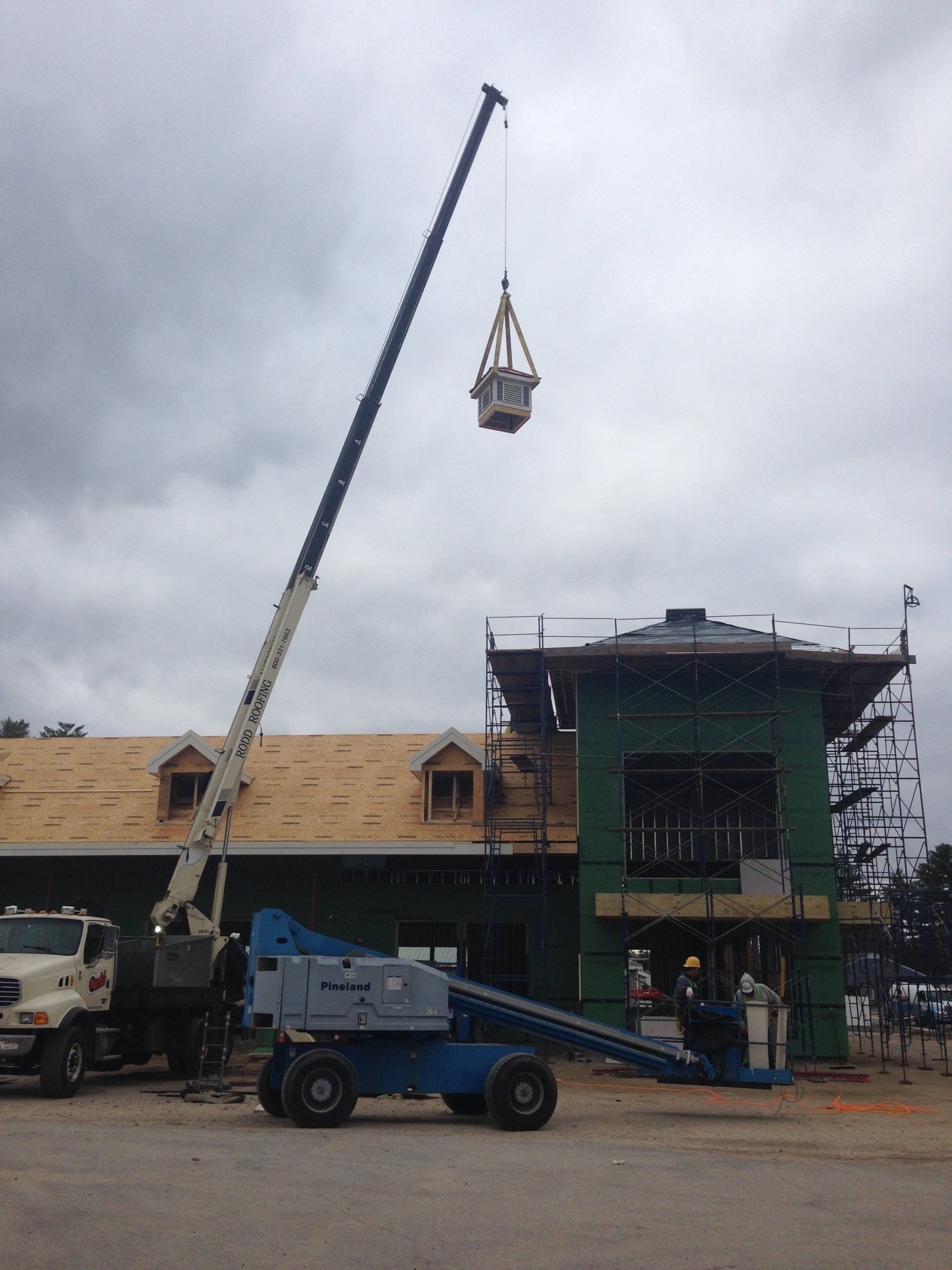 A crane is lifting a container over a building under construction