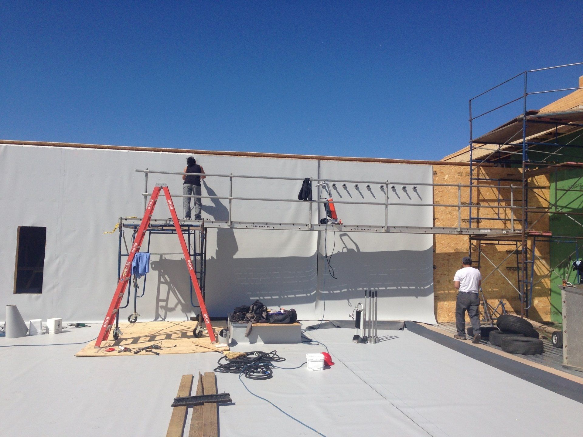 A man is standing on a ladder in front of a building under construction