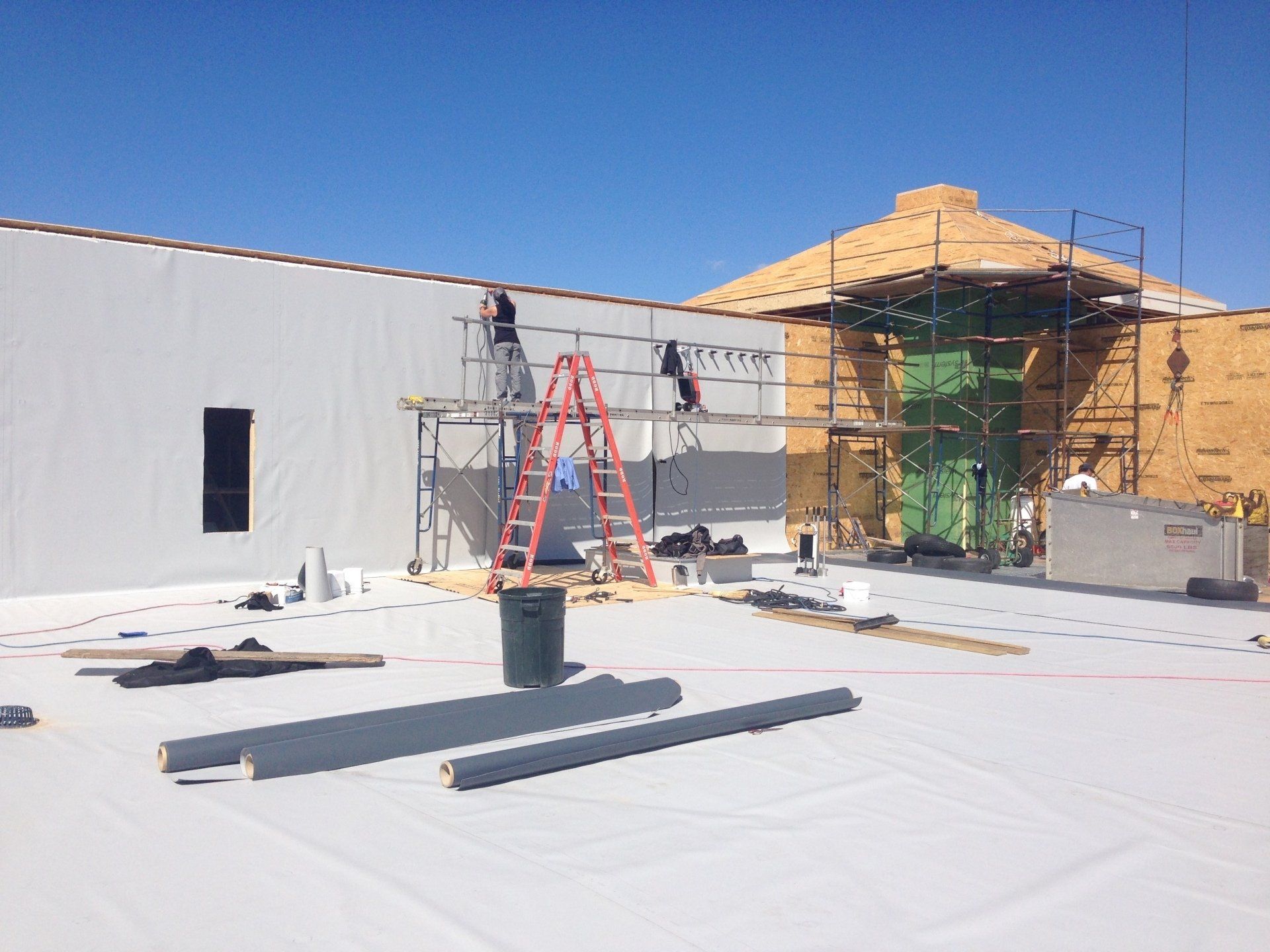 A building is being built with scaffolding and a ladder on the roof.