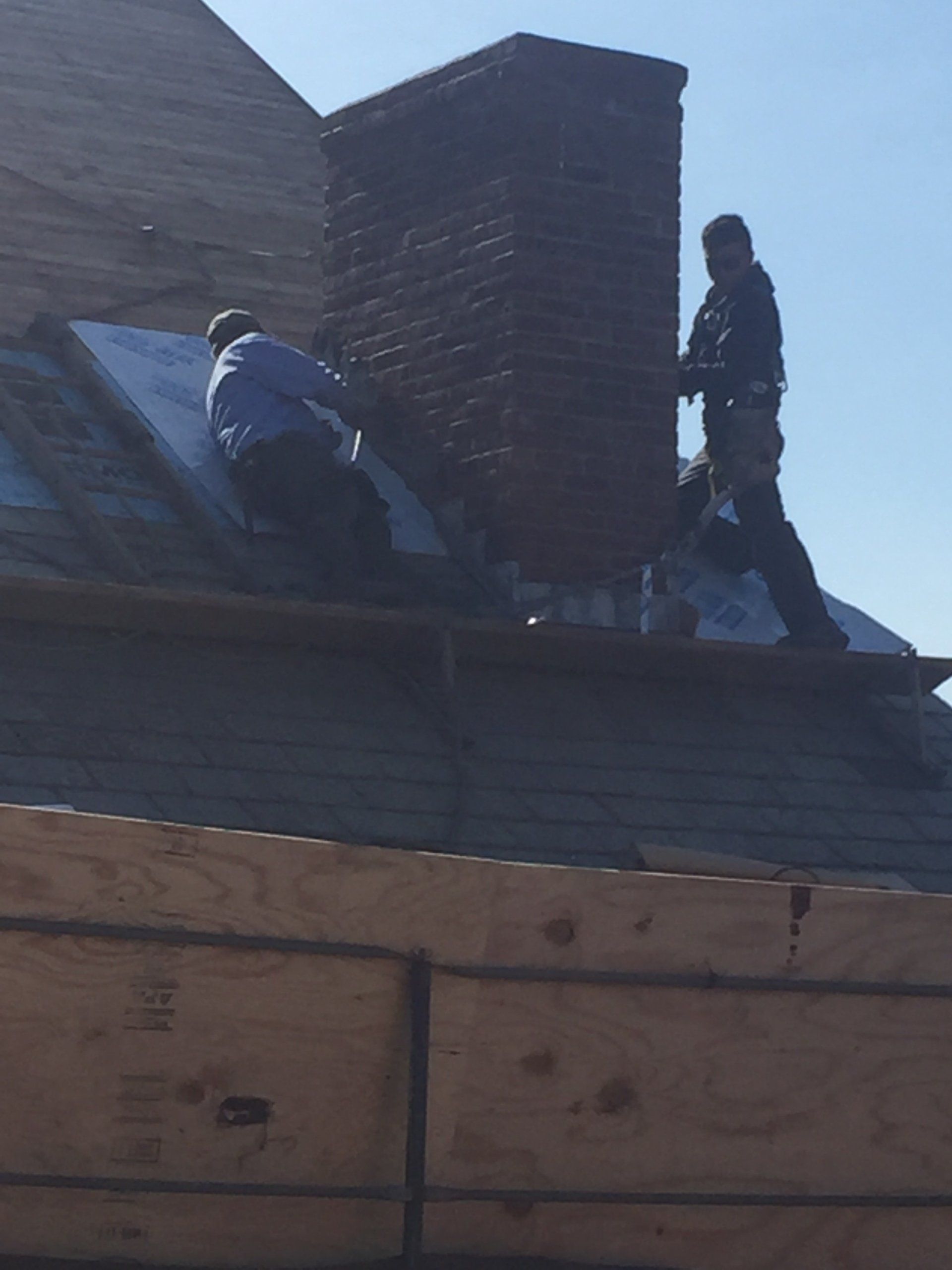 Two men are working on the roof of a house