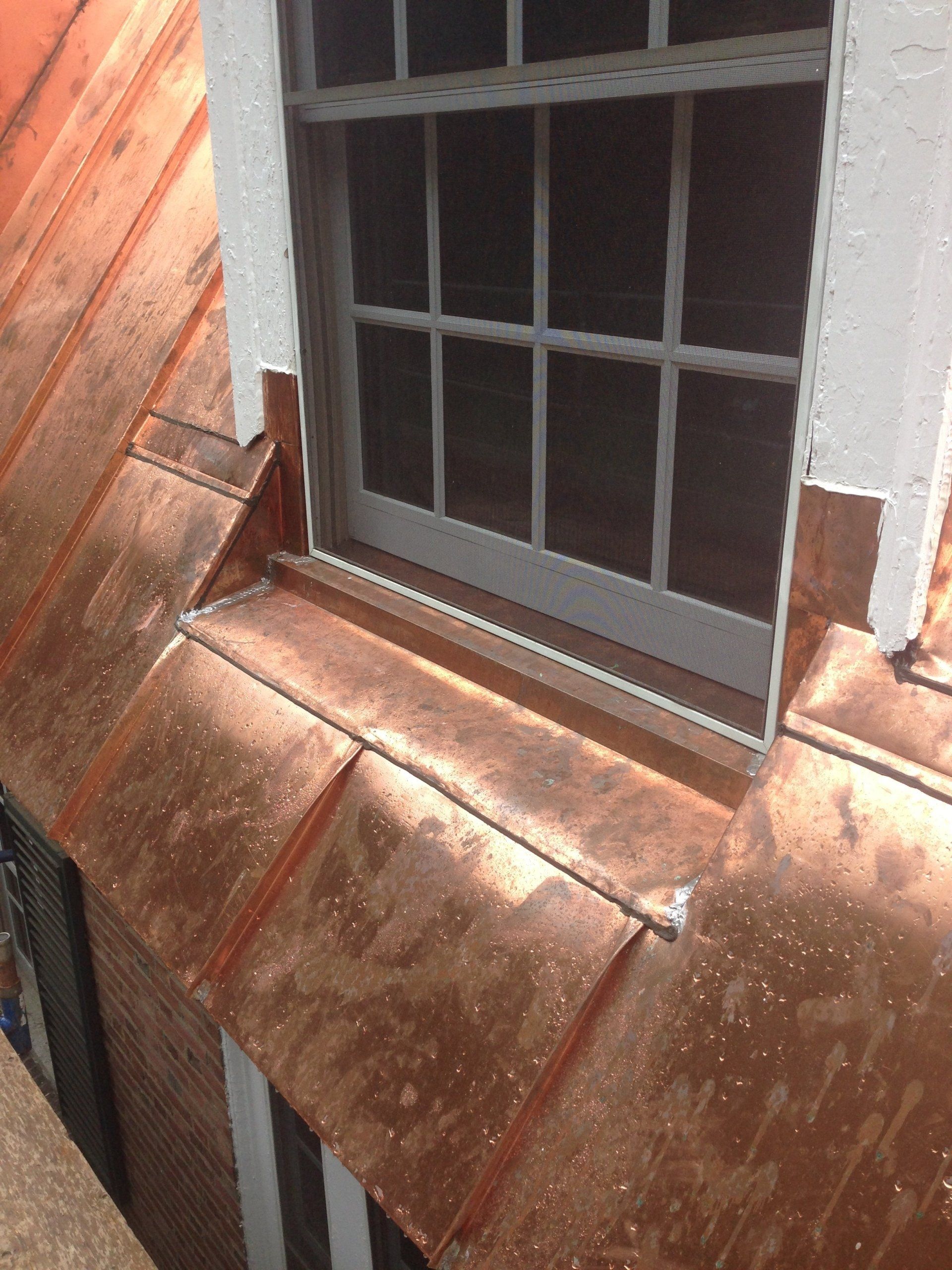 A window on the side of a building with a copper roof