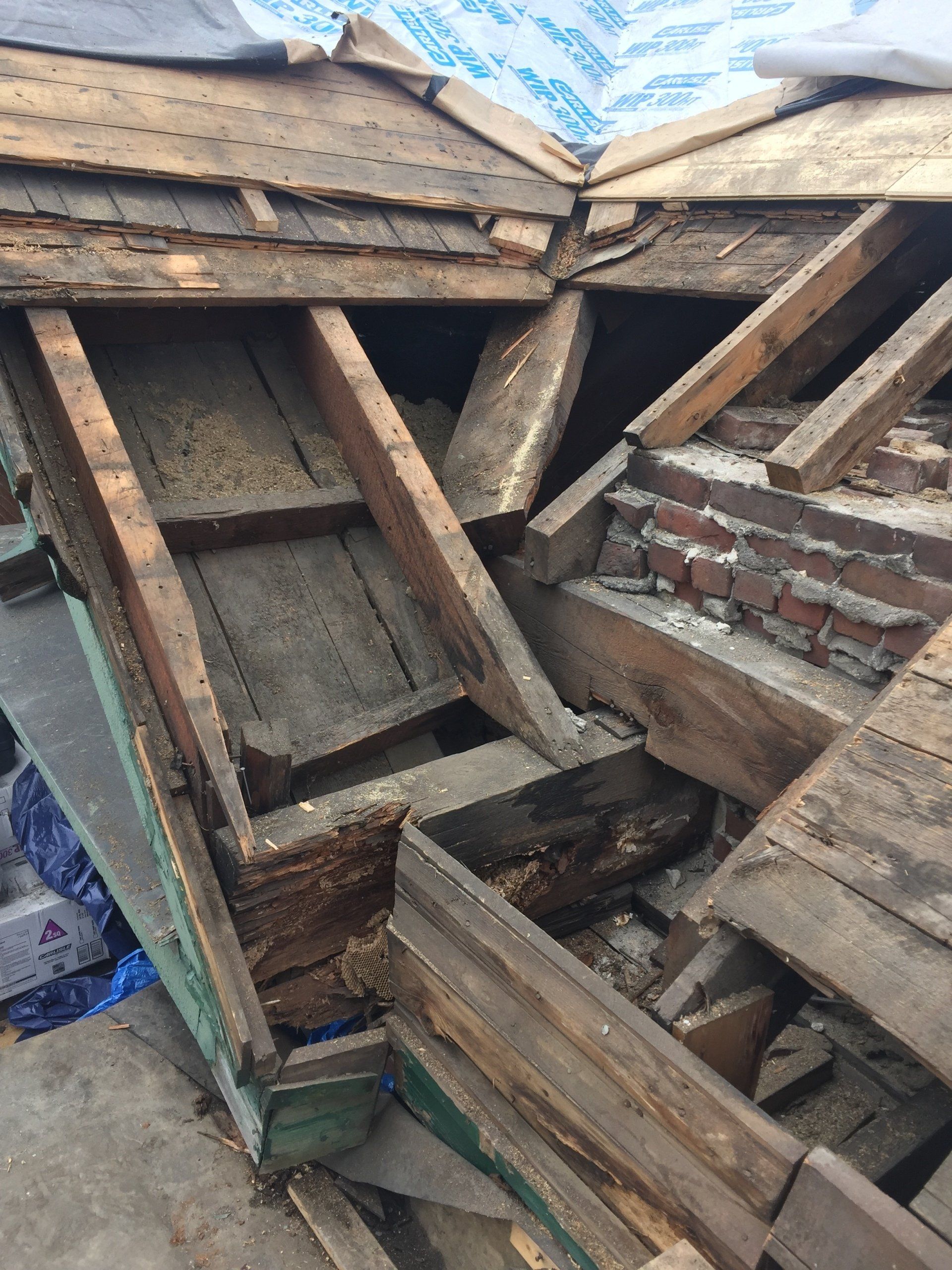 A pile of wood is sitting on top of a brick wall.