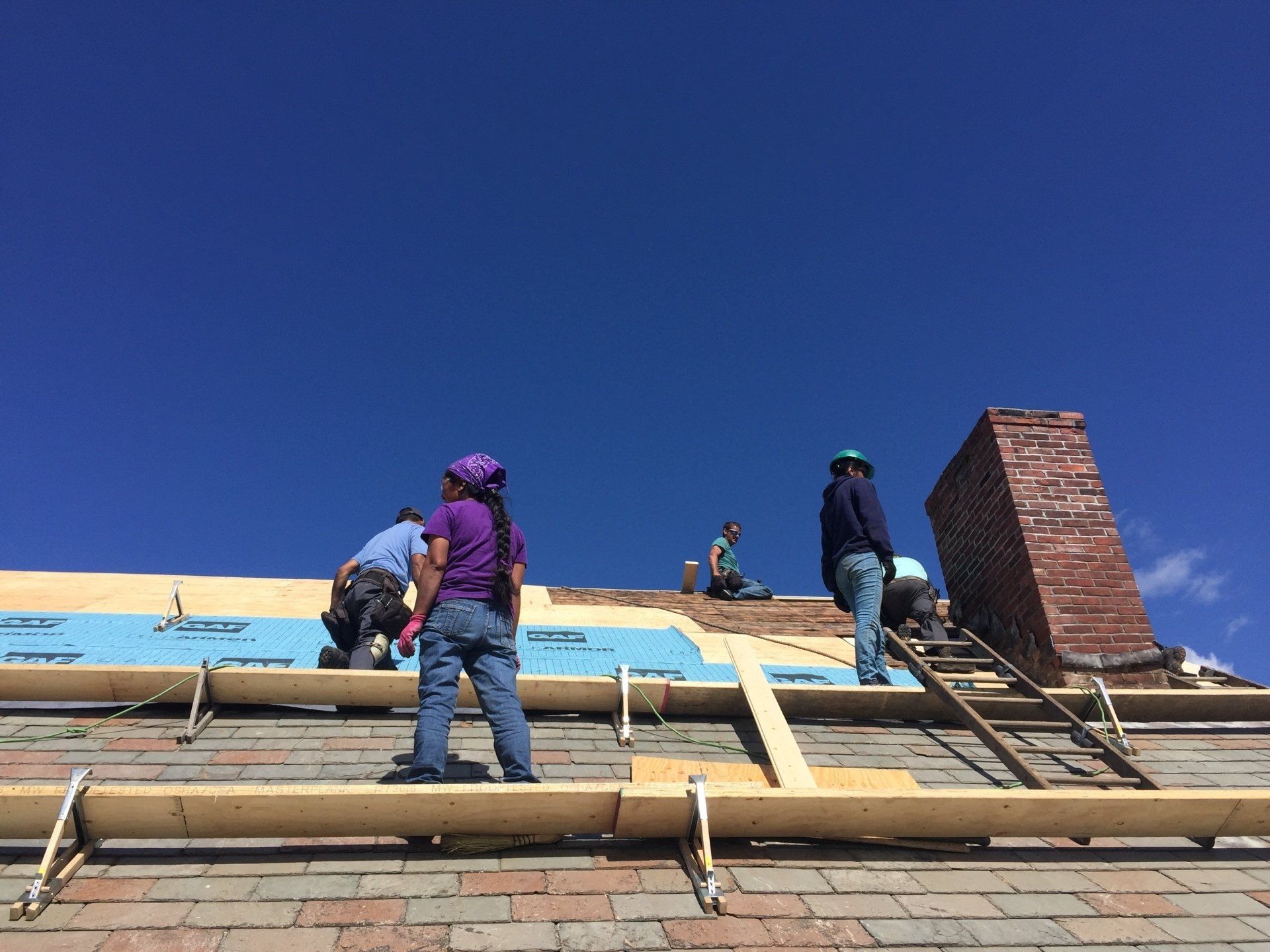 A group of people are working on the roof of a building.