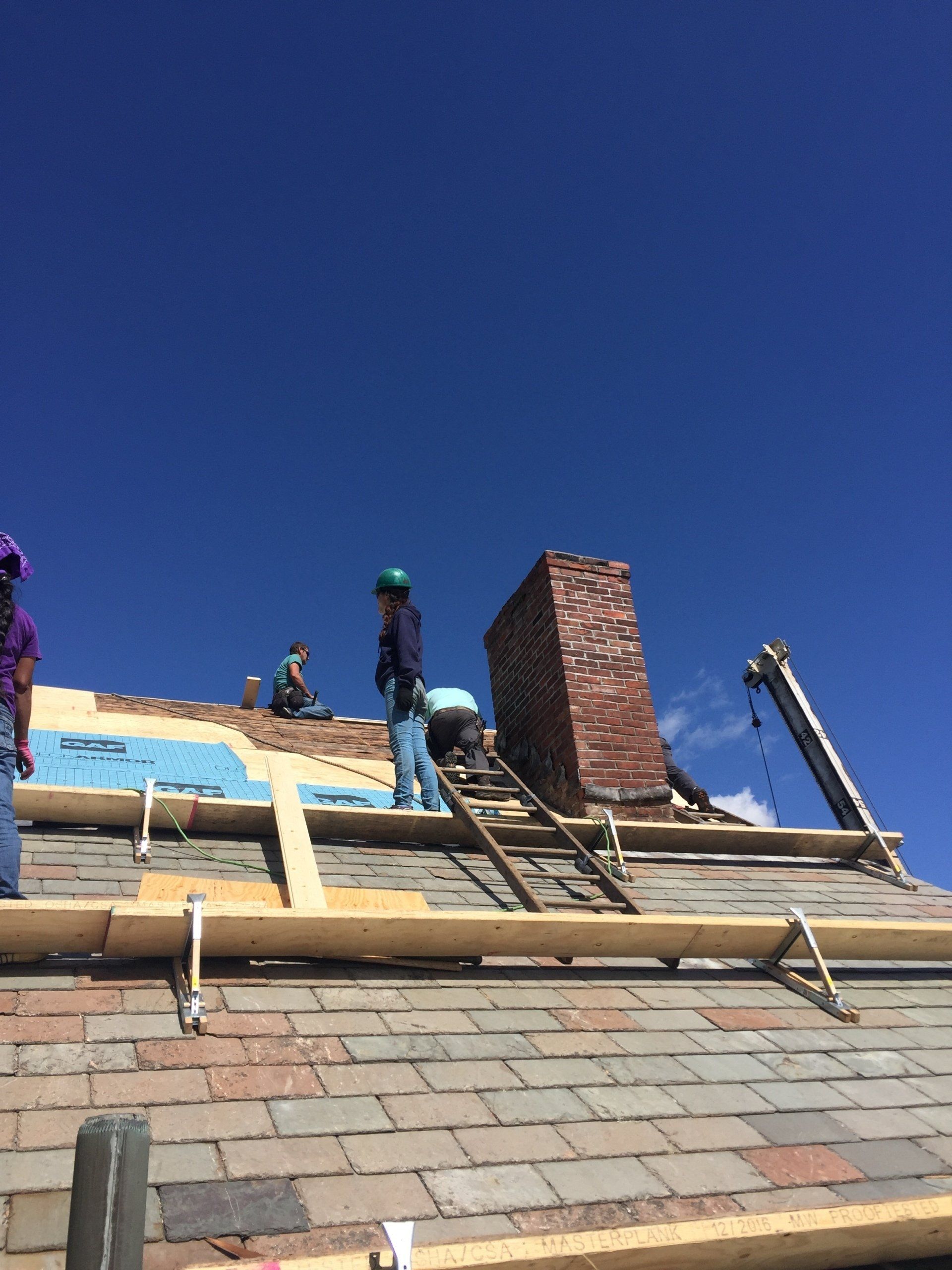 A group of people are working on the roof of a building.