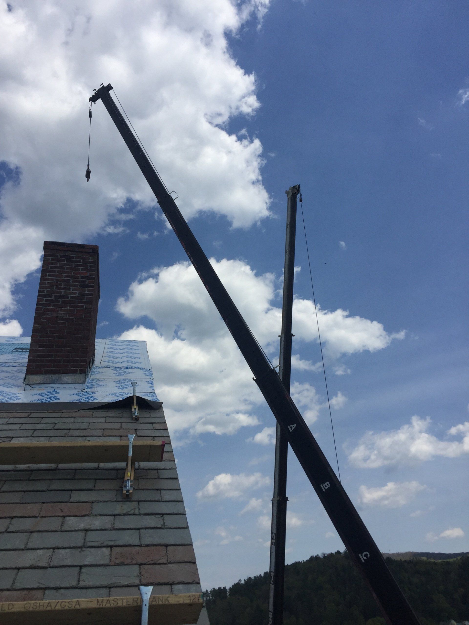 A crane is being used to remove a chimney from a roof
