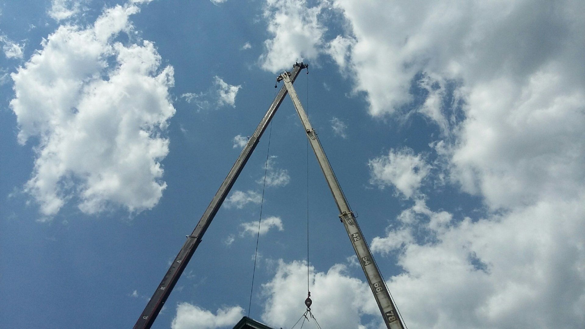 A crane is lifting a large object in the sky.