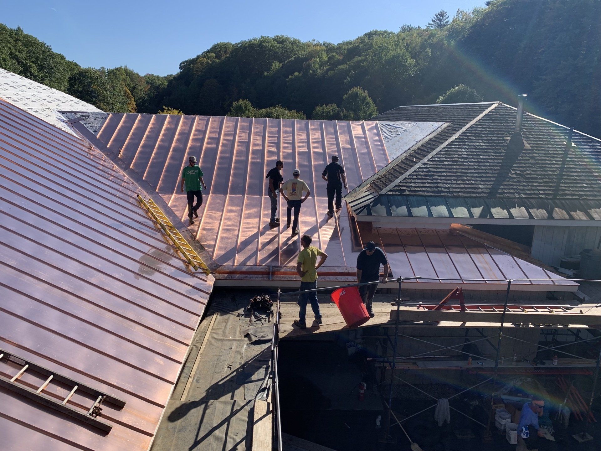 A group of people are standing on top of a copper roof.