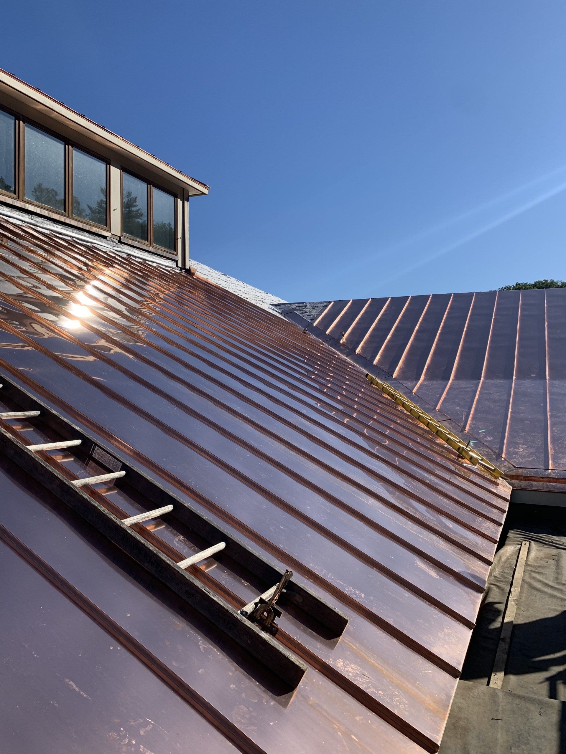 A roof with a ladder on it and a blue sky in the background