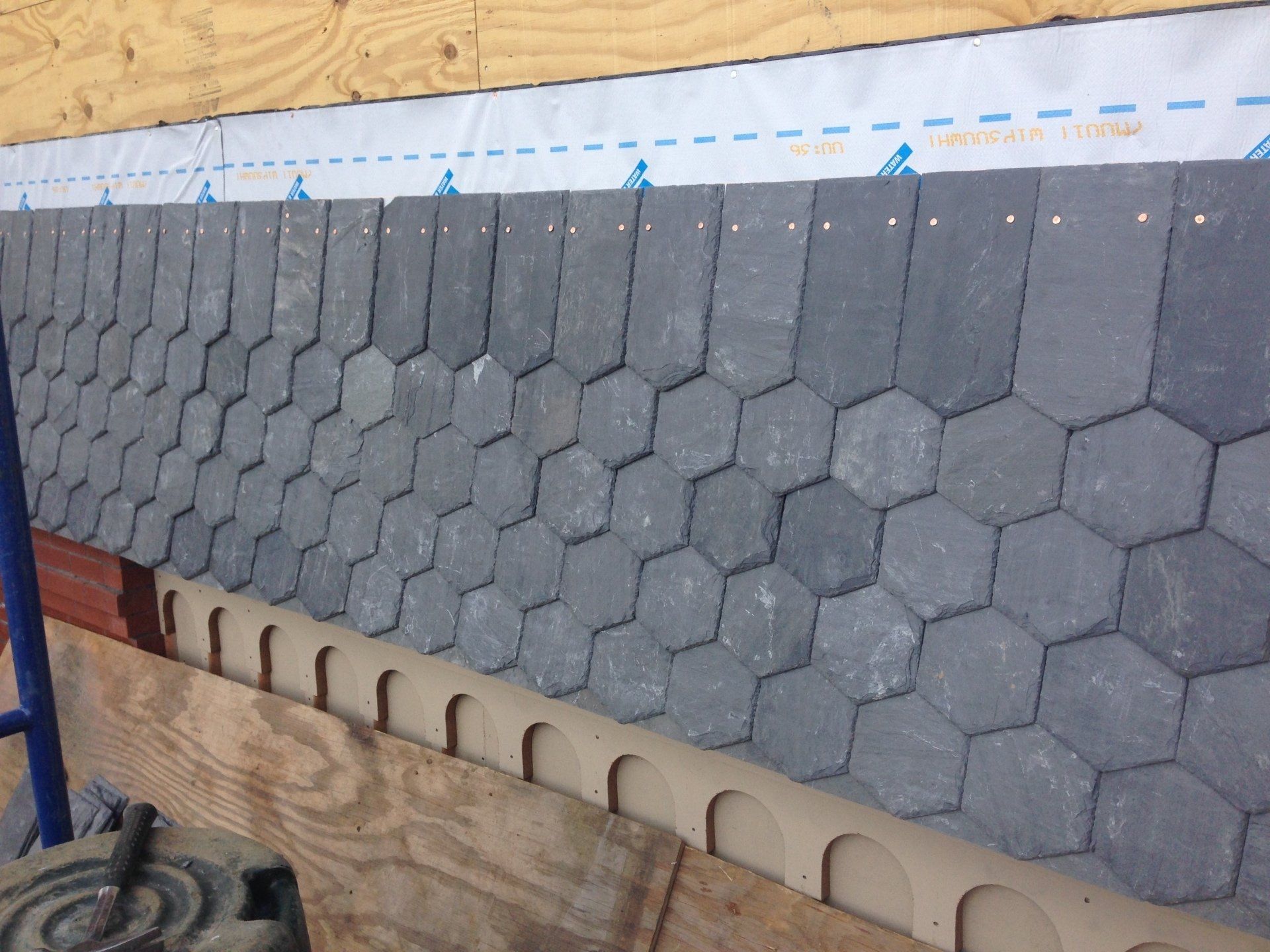 A roof that is being built with hexagonal tiles