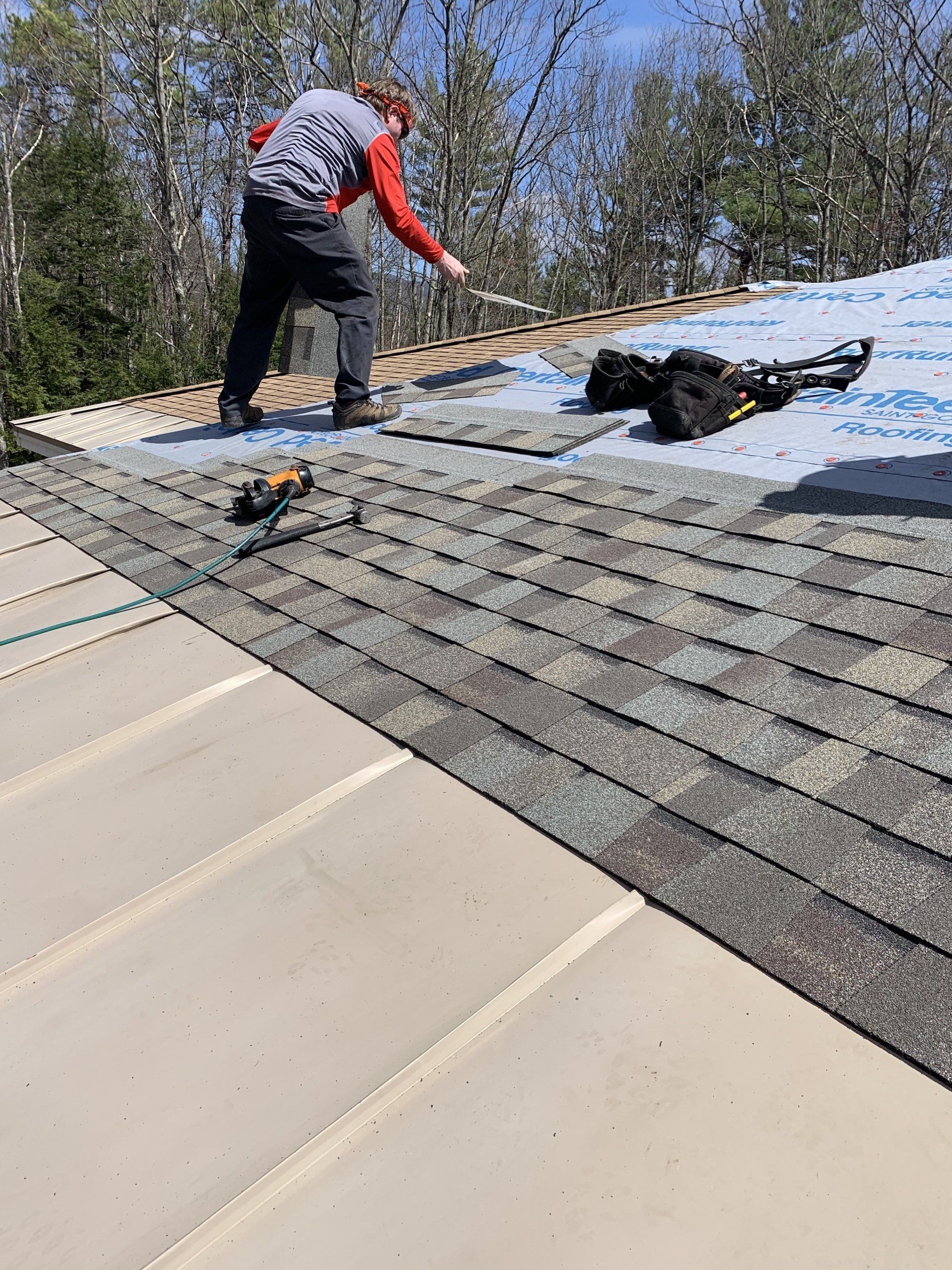 A Rodd Roofing employee is working on the asphalt shingles on the roof of a house in Vermont