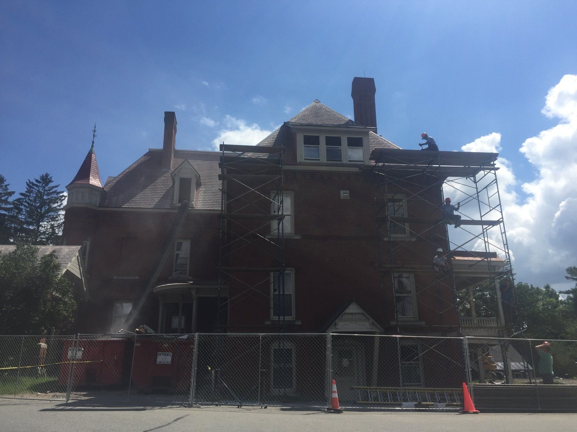 A large brick building with scaffolding around it is being remodeled.