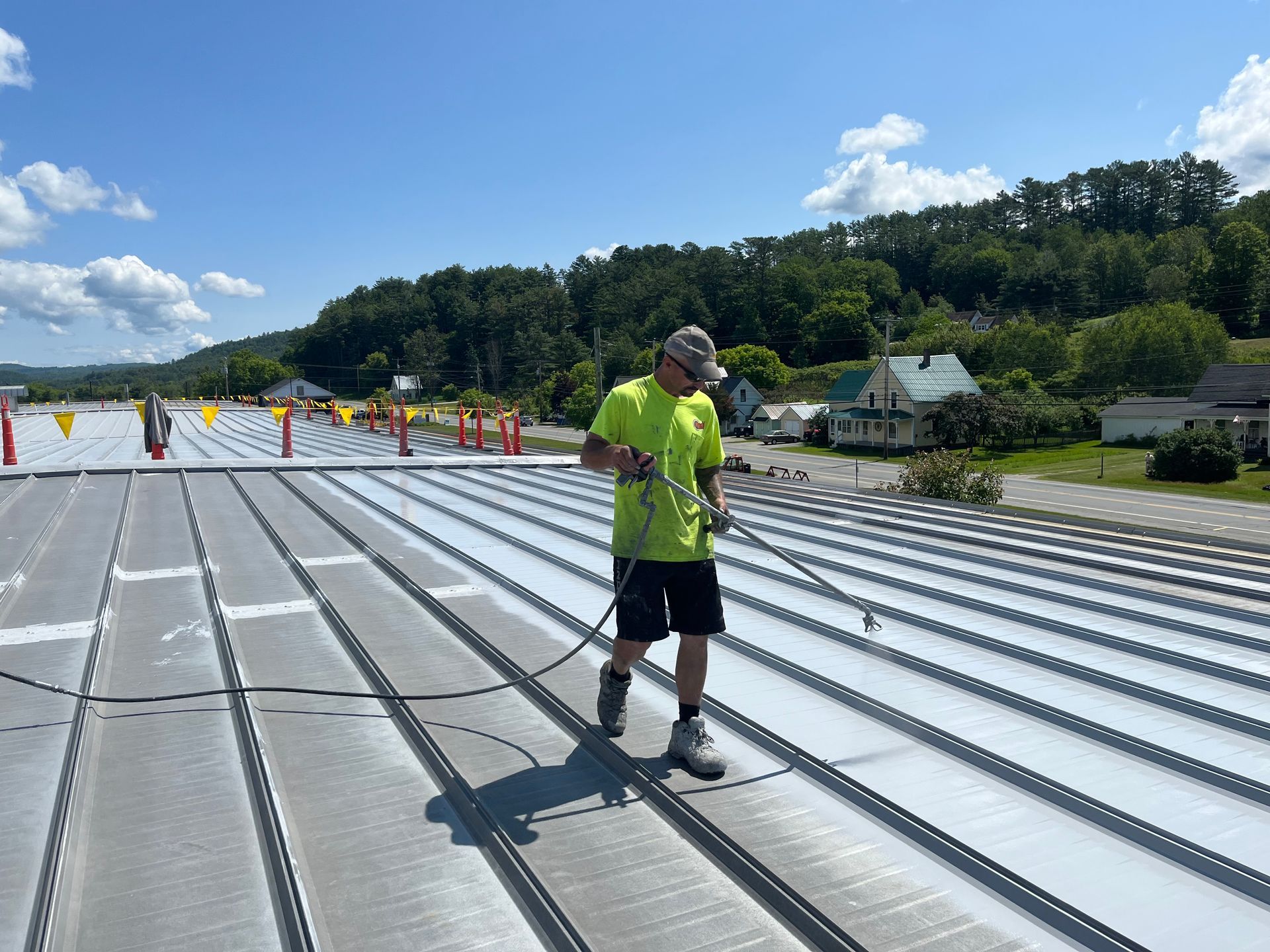 A Rodd Roofing employee applying a silicone roof coating to a commercial roof in Vermont