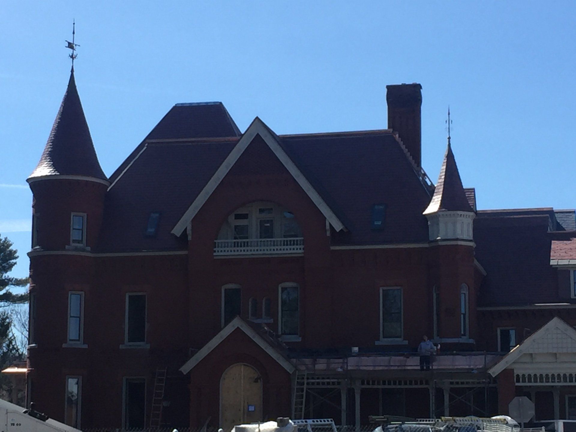 A large brick building with a red roof and a weather vane on top