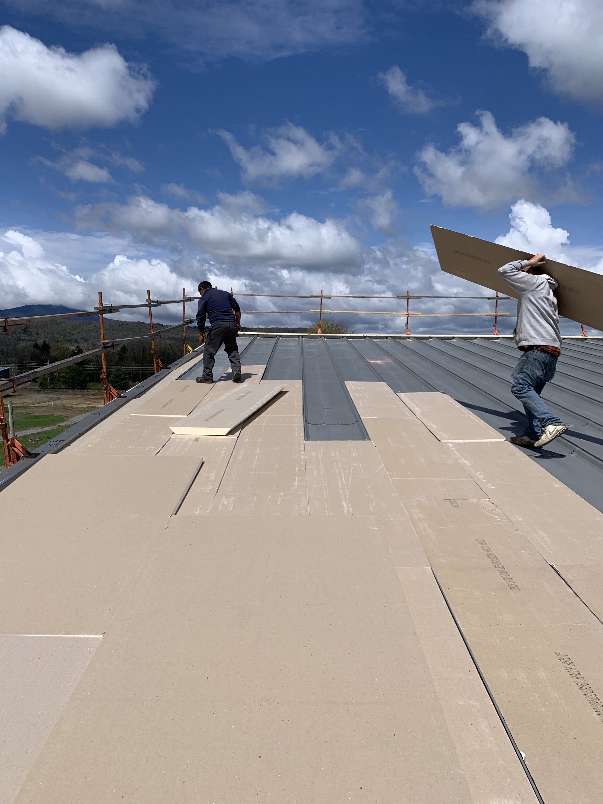 Two men are working on the roof of a building.