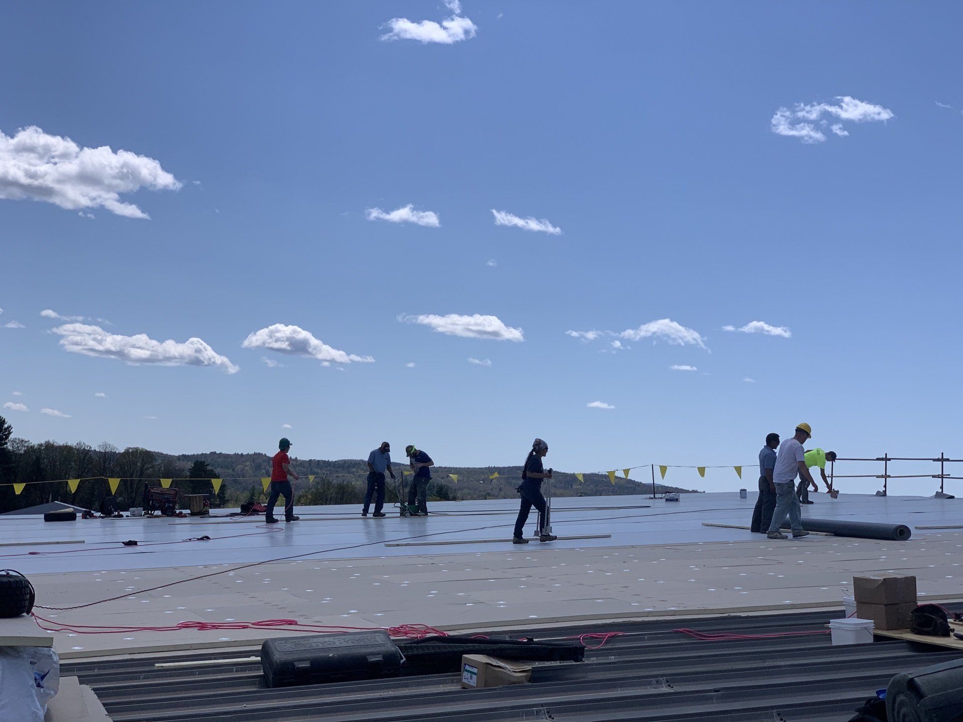 Rood roofing employees coat flat commercial roof in New Hampshire