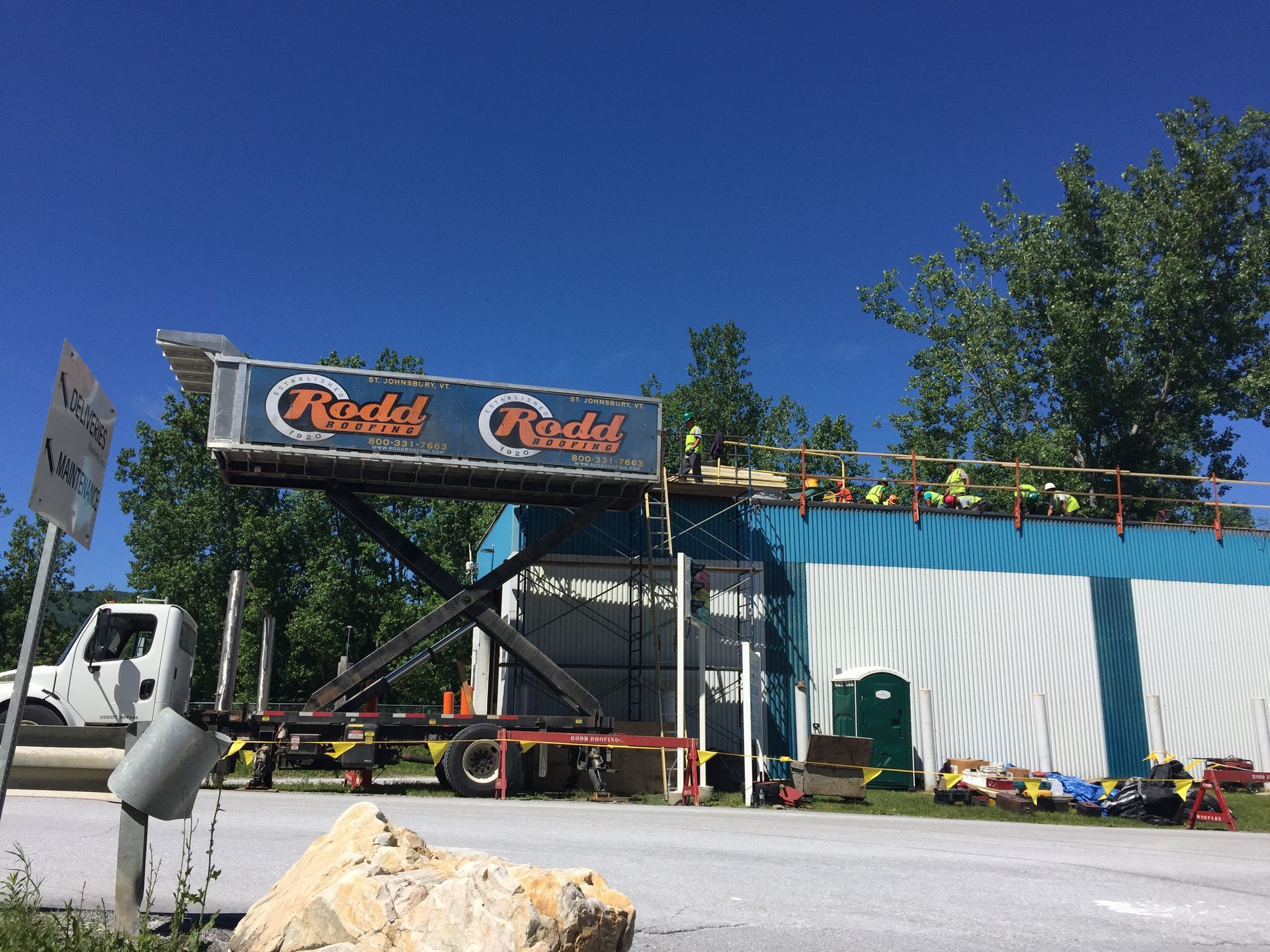 Rodd Roofing truck parked at a job site with men working on the roof