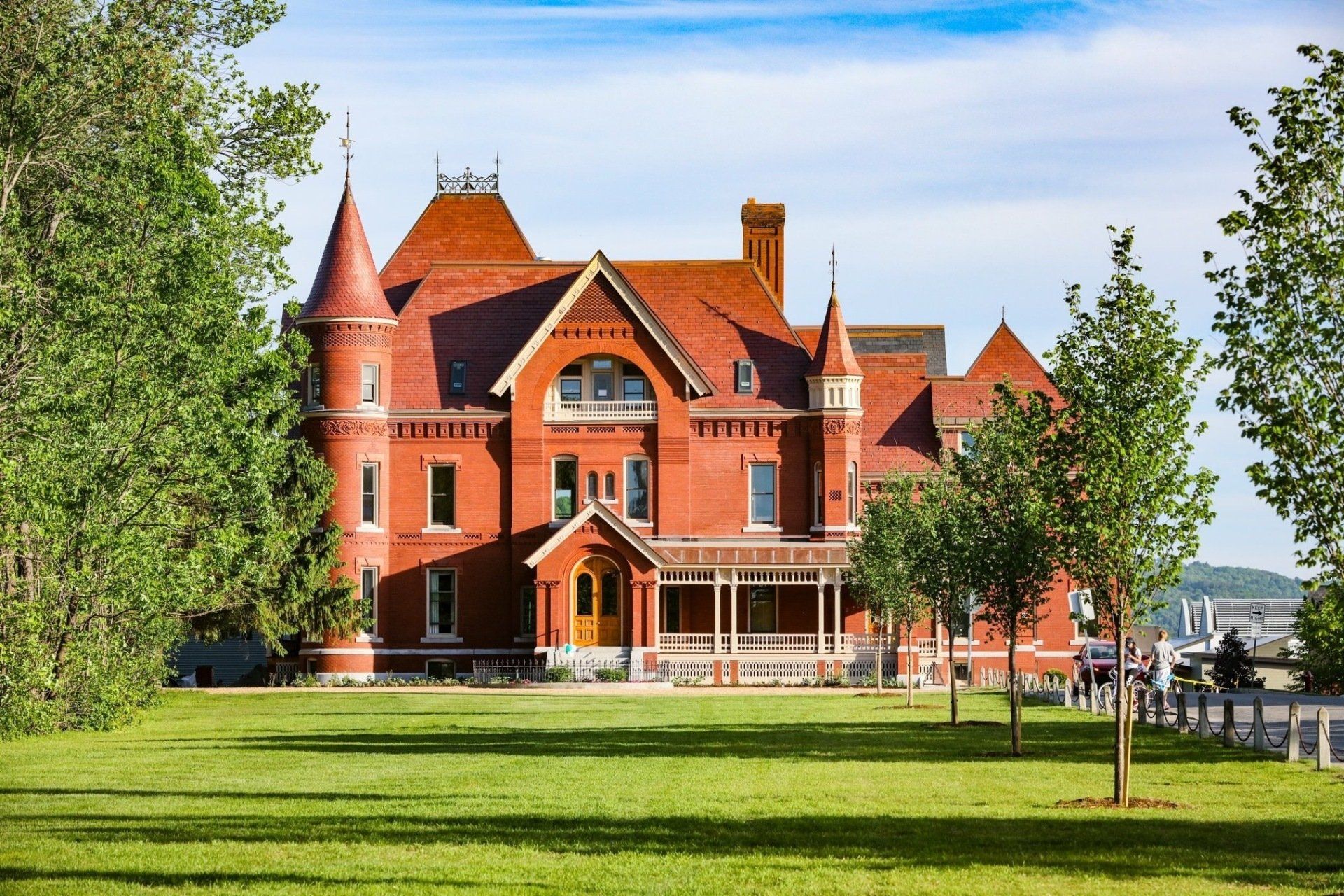 A large red brick house is sitting on top of a lush green field.