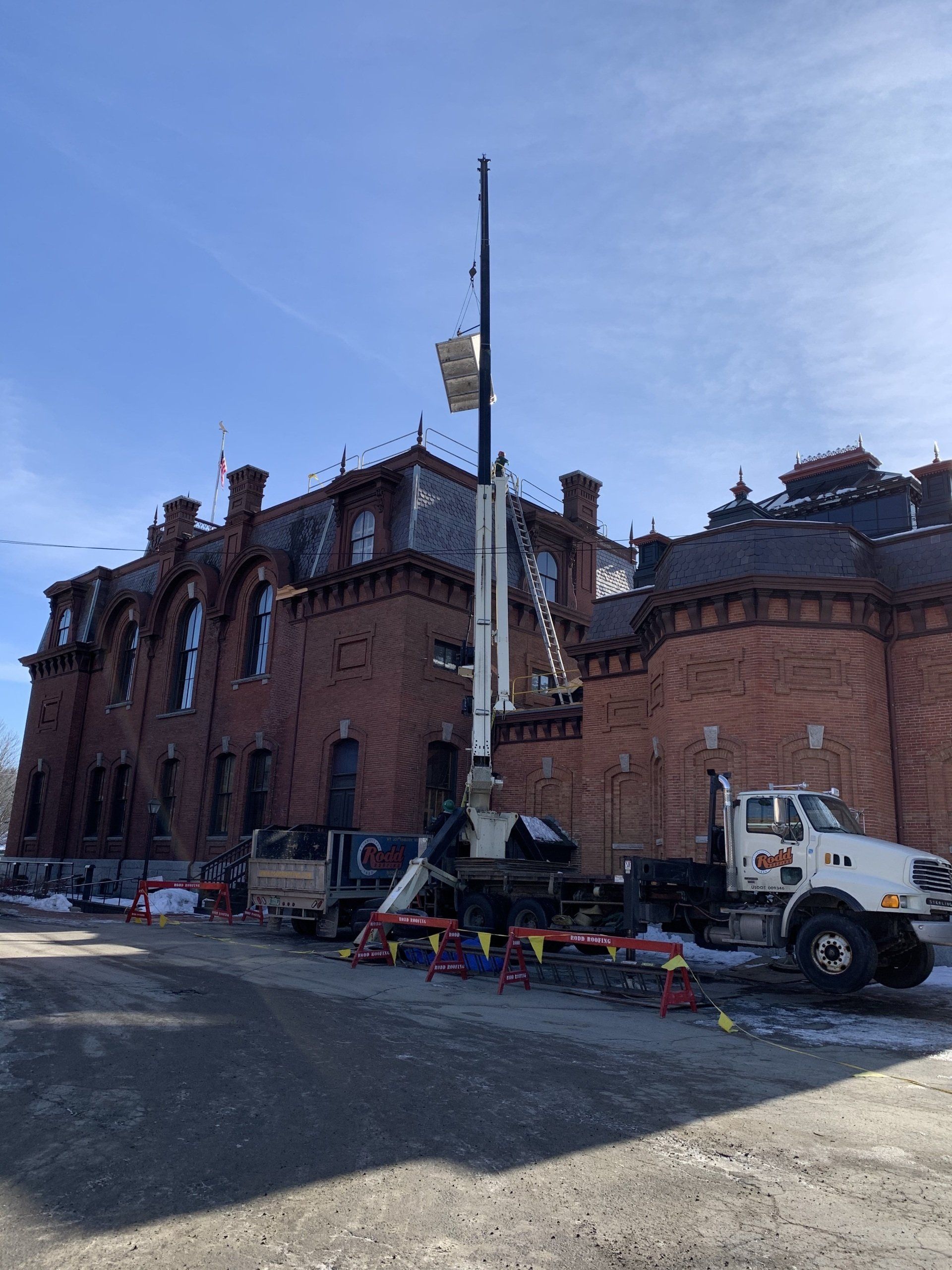 Rodd Roofings ladder truck lifting supplies to the roof of a commercial building